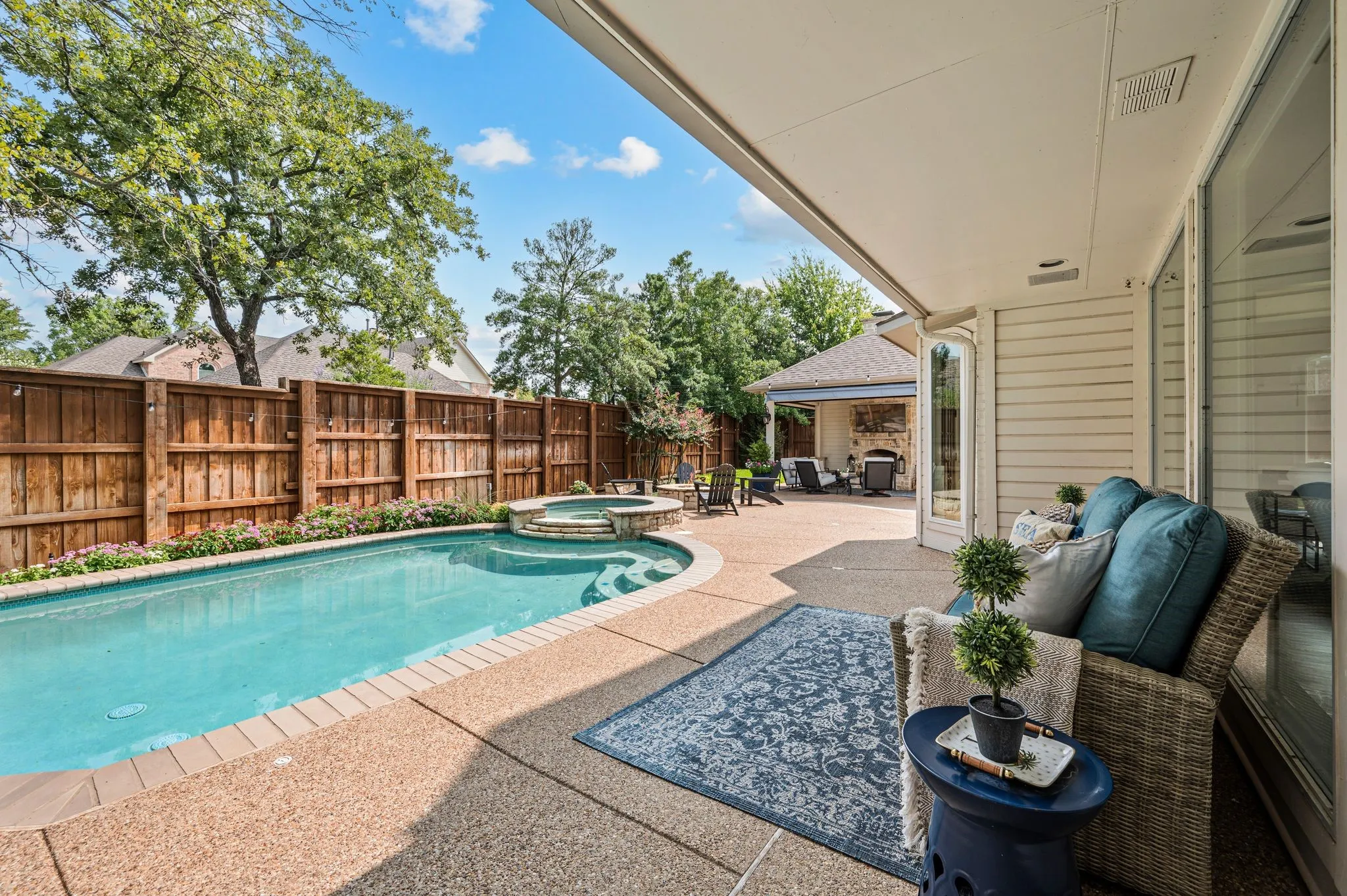 The backyard begins just beyond the living room, where the pool and spa sit beneath mature trees and the covered spaces make it easy to stay outside throughout the day.