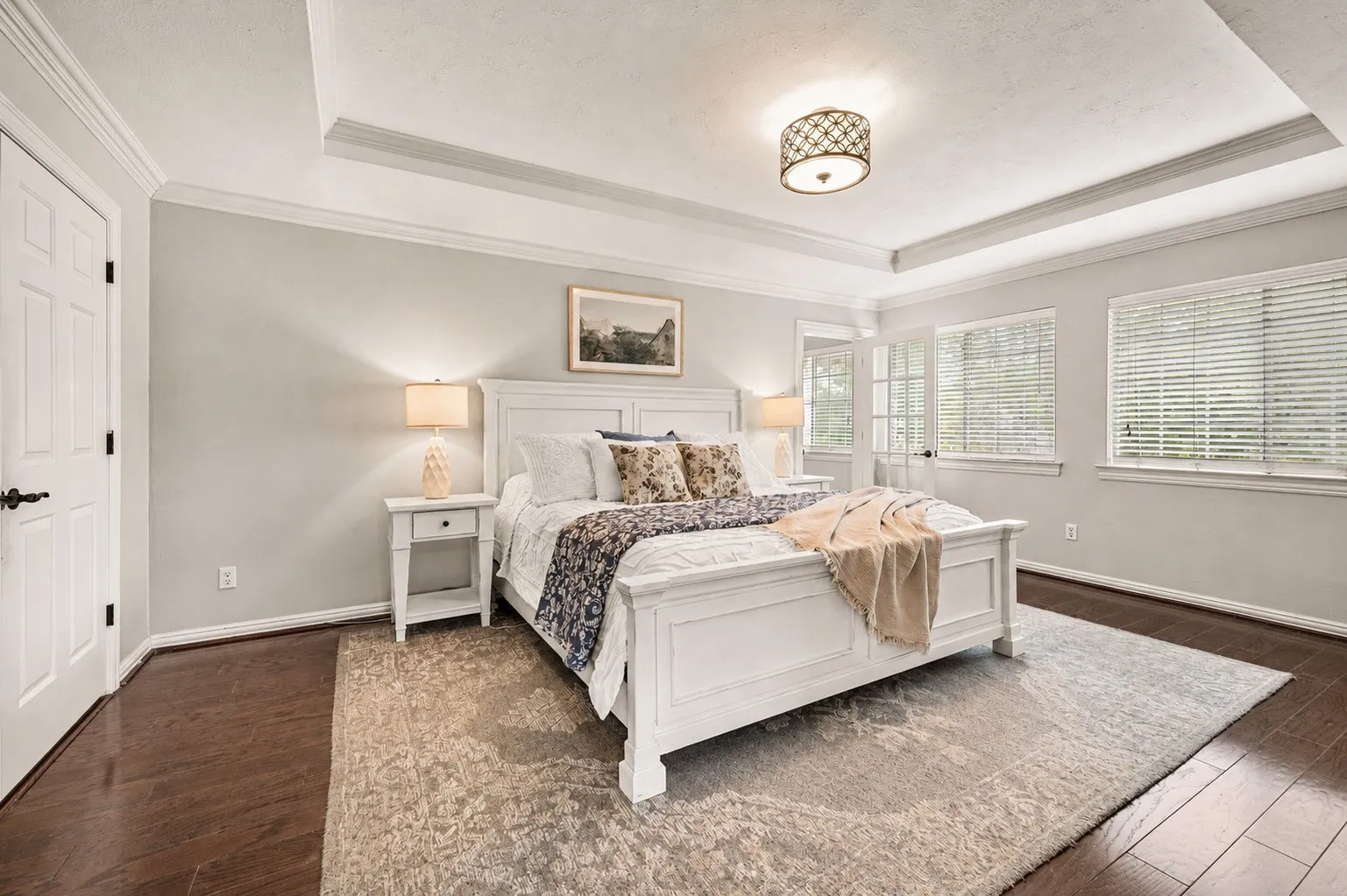 The owner's suite feels calm and removed from the rest of the home, with layered ceilings, dark wood floors and windows that bring in soft natural light.