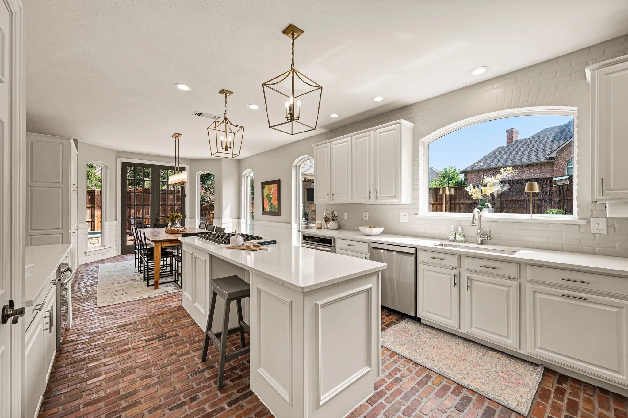 From the kitchen, arched windows and French doors keep the backyard constantly in view, reinforcing the connection between indoors and out.