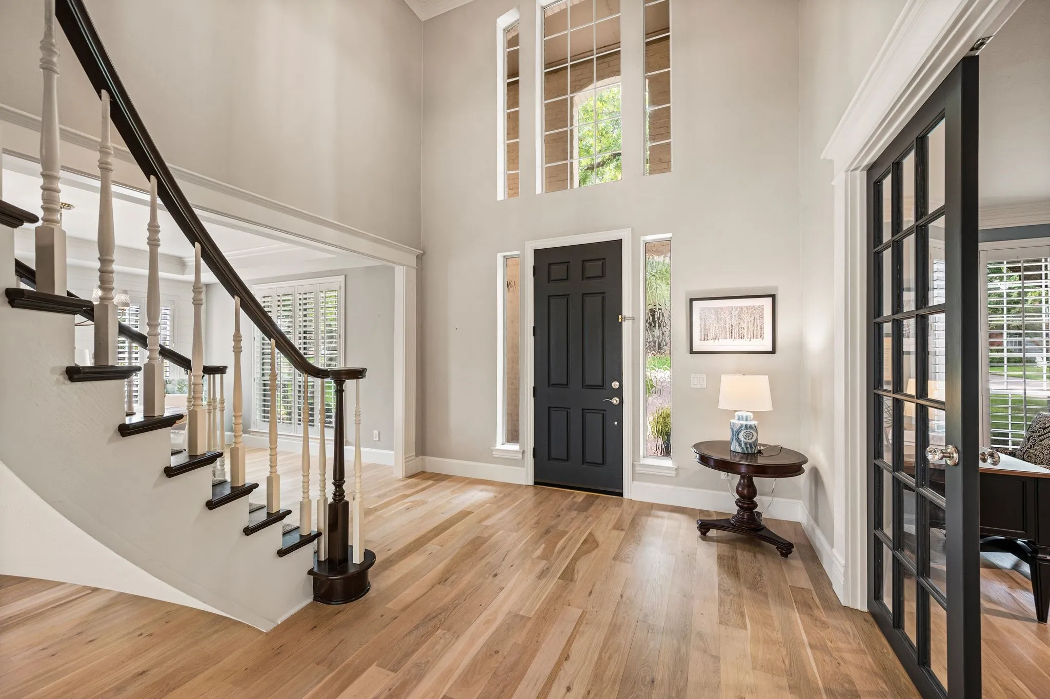 The two-story entry introduces the home with warm wood floors, a graceful staircase and the first glimpse of the collected interiors beyond.