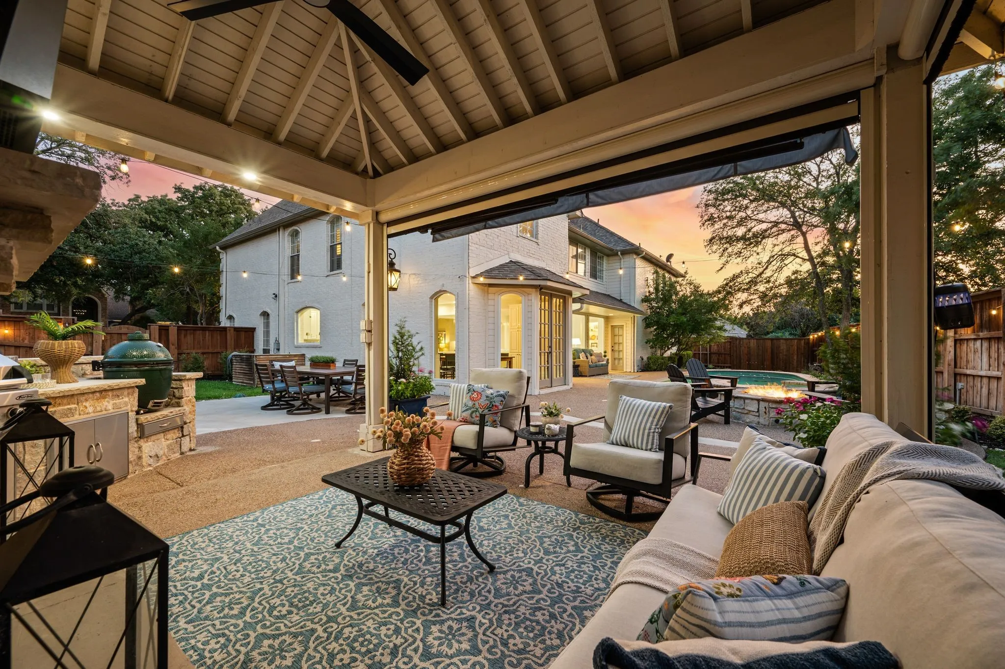 From the covered living space, evenings unfold easily between the fireplace, outdoor kitchen, fire pit and pool.