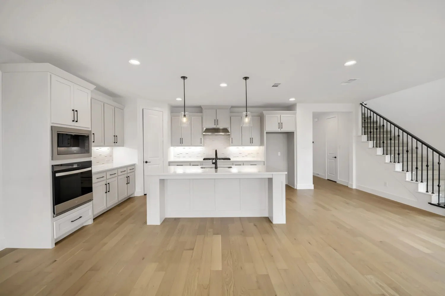 Open-concept kitchen with a central island, recessed lighting, stainless steel appliances, and wood-finish flooring