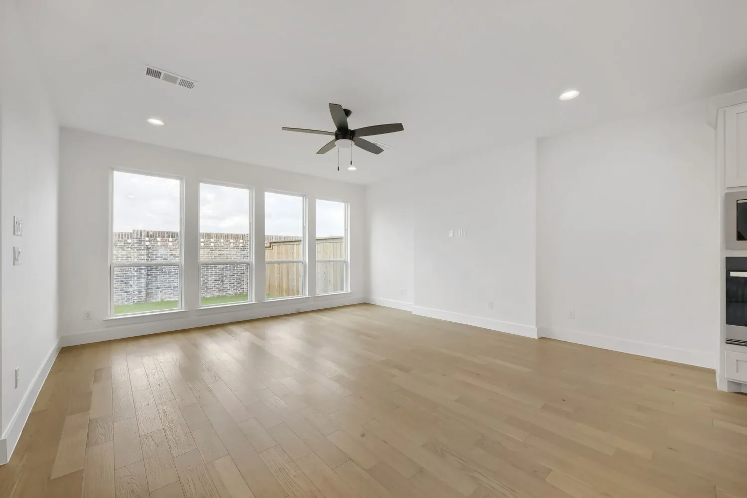 Family room with a wall of windows, recessed lighting and ceiling fan