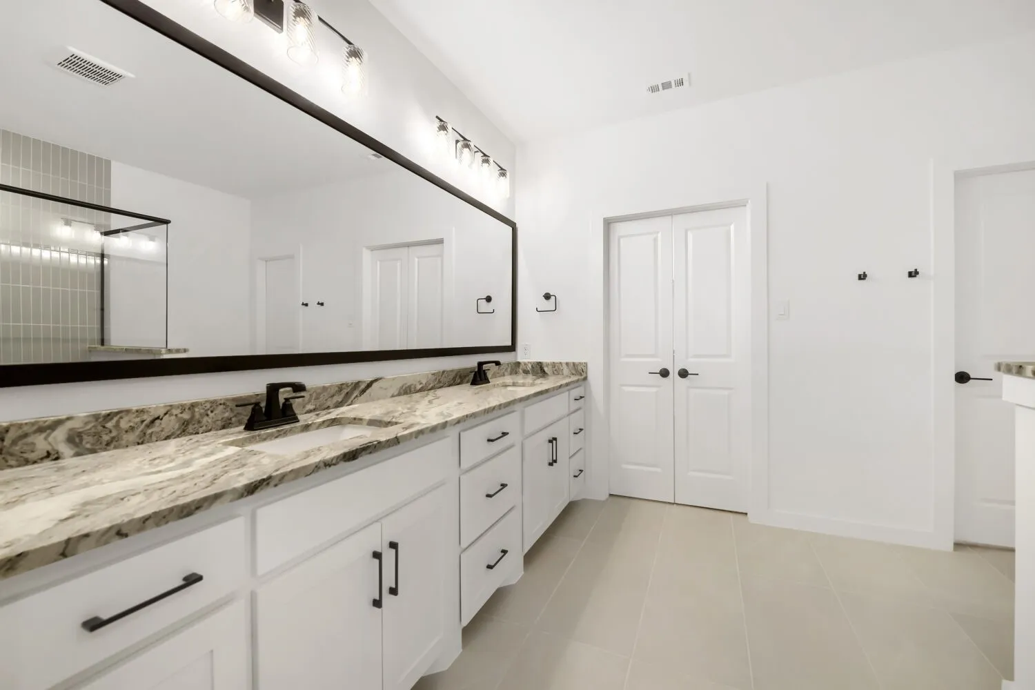 Dual vanity with integrated sinks, rich stone countertops, and matte black hardware