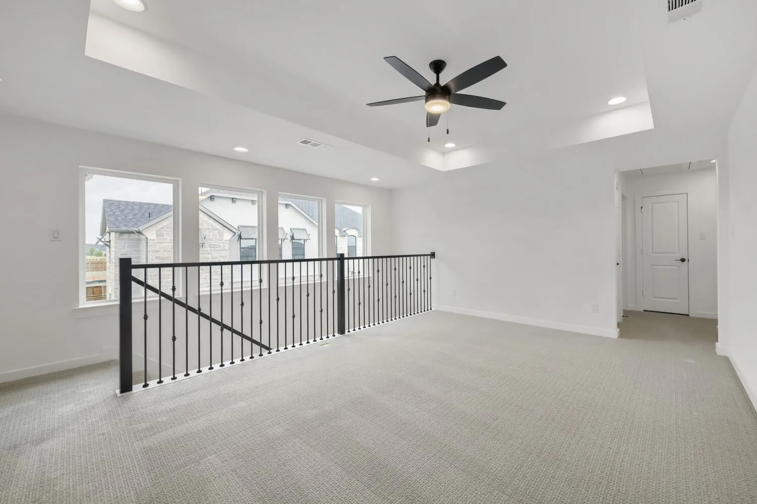 Spacious open loft with carpeted flooring, multiple windows, a ceiling fan, and recessed lighting