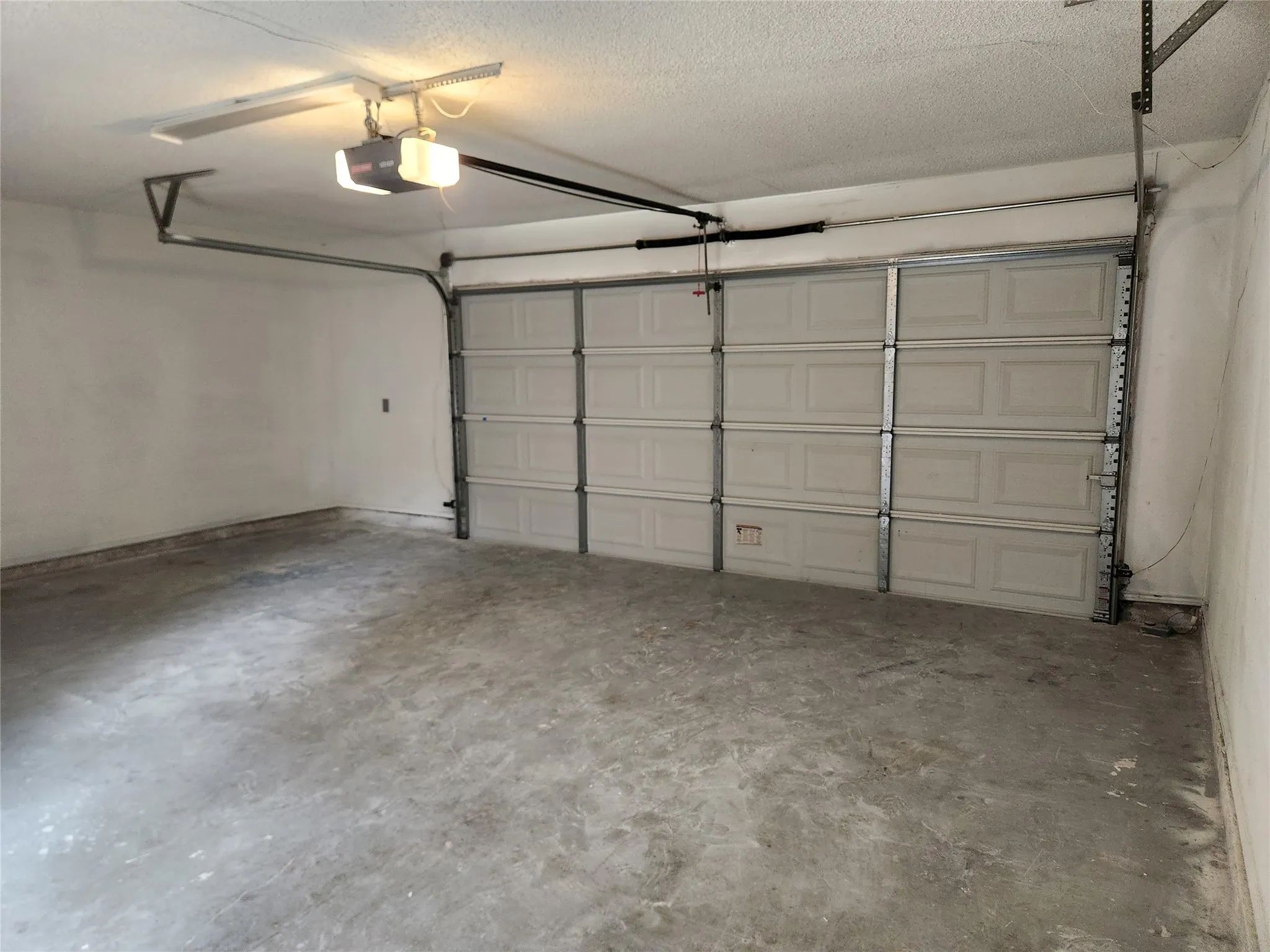 Attached garage featuring an automatic opener, concrete flooring, and painted walls