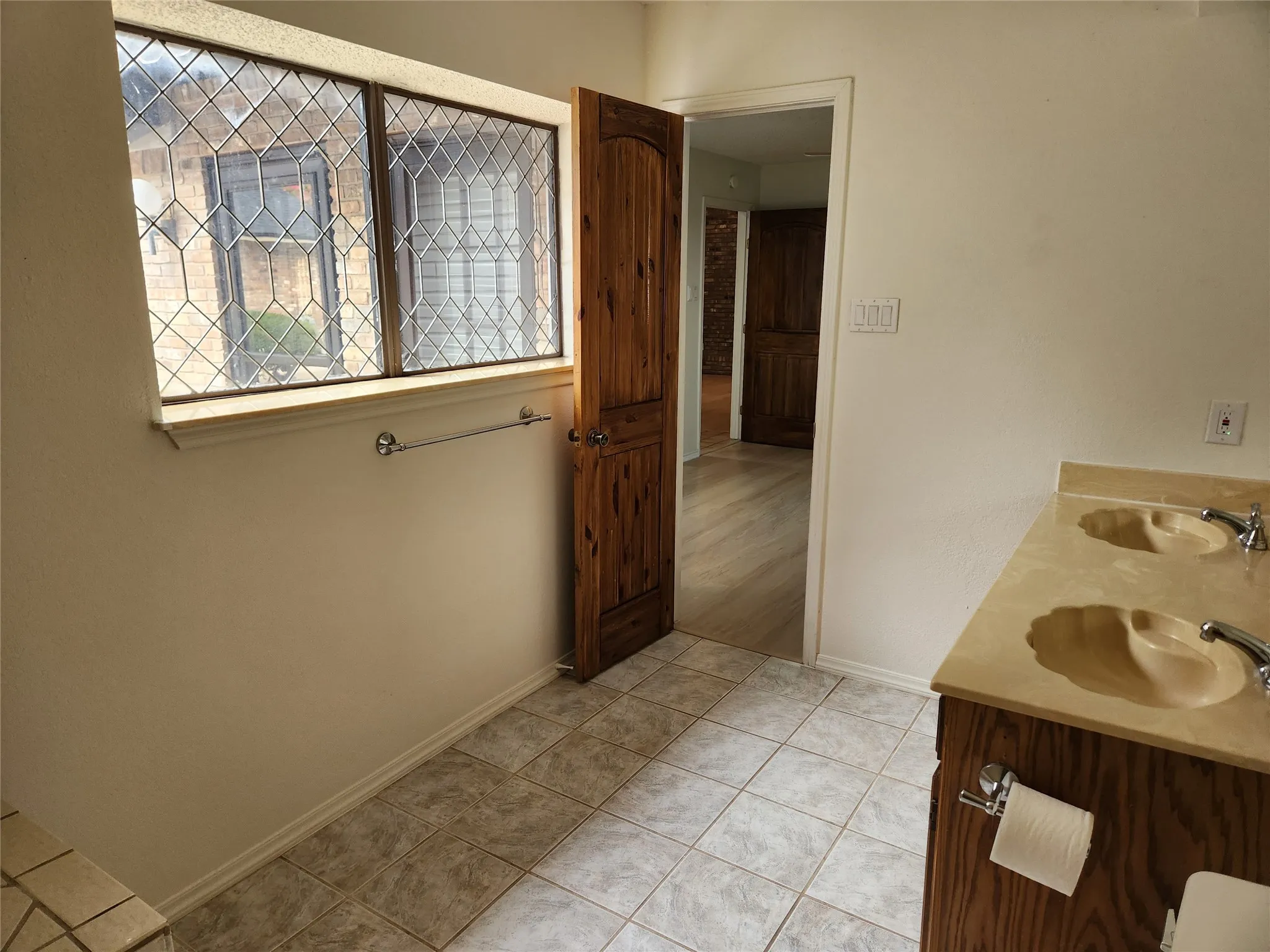 Bathroom featuring a wood-finish vanity with a light-toned countertop, a white toilet, a white bathtub, and white square wall tiles