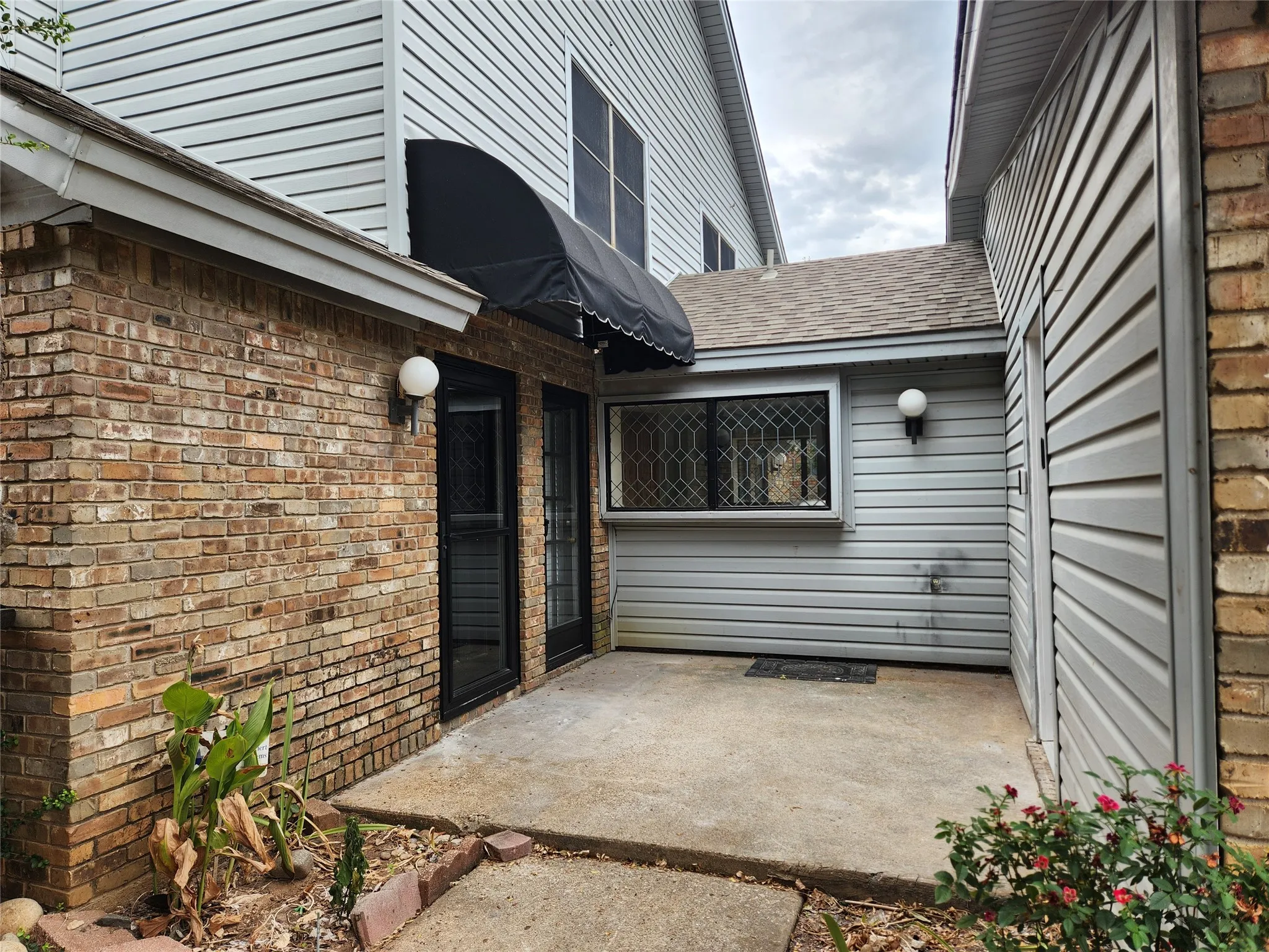Brick and siding exterior with a concrete patio