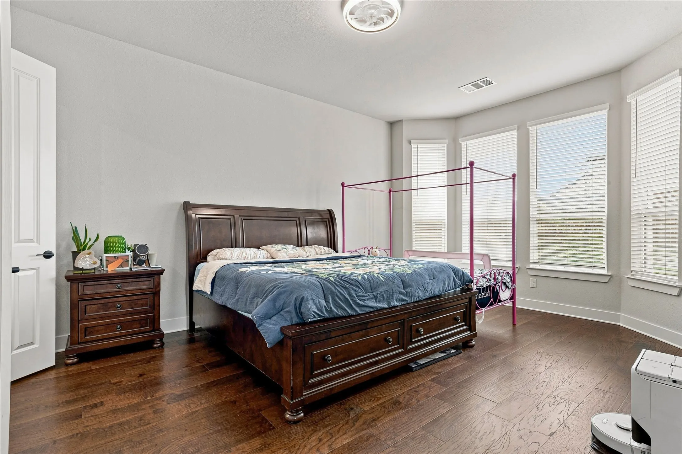 Wood-finish flooring throughout, bay windows with blinds, and white walls