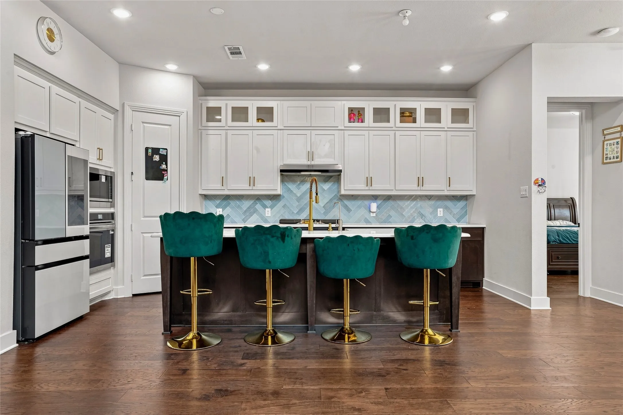 Gourmet kitchen featuring white cabinetry, a herringbone tile backsplash, and a central island with a contrasting base