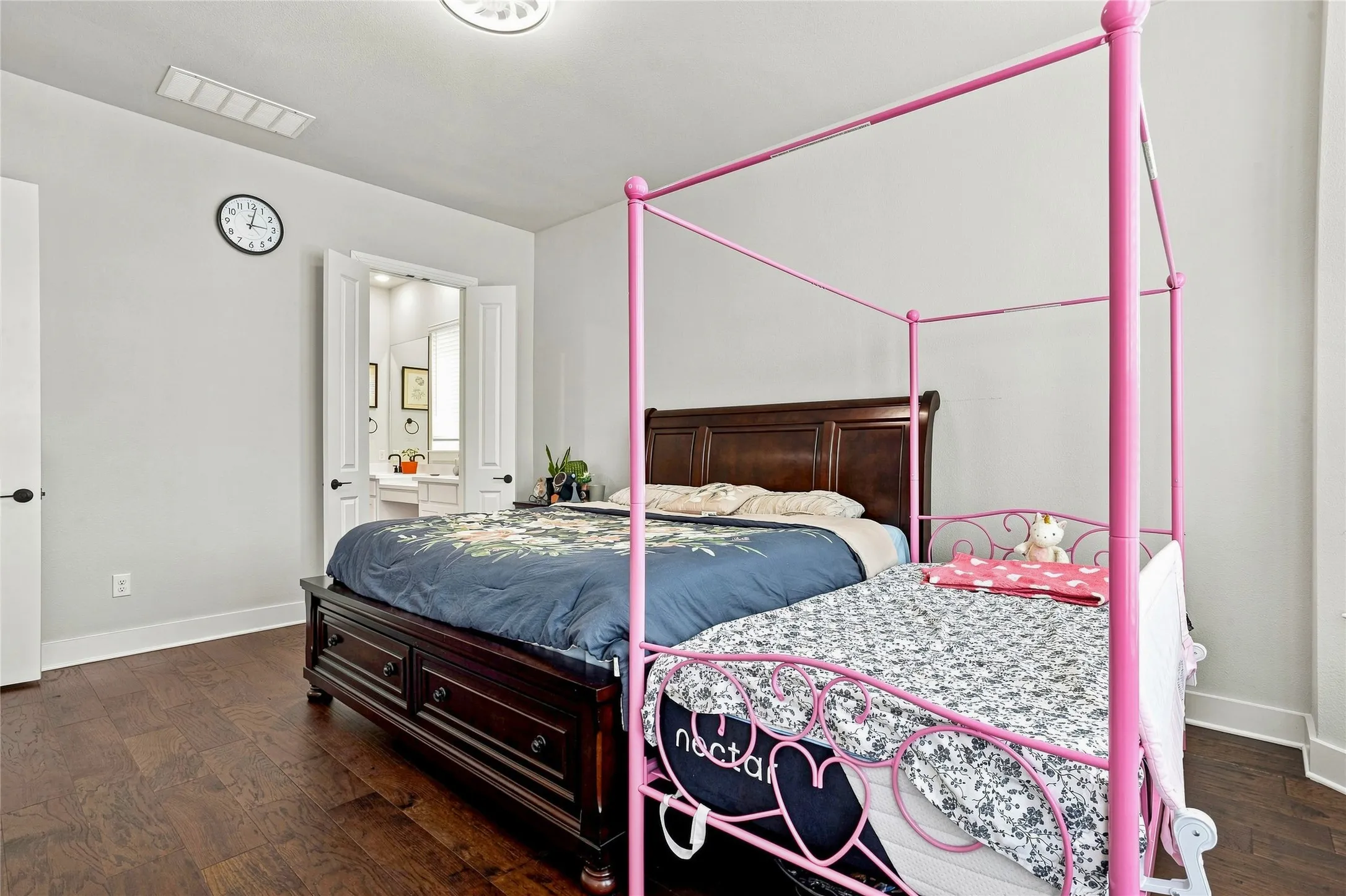 Hardwood flooring, light gray wall paint, white trim, recessed lighting, and double doors to an adjoining bathroom