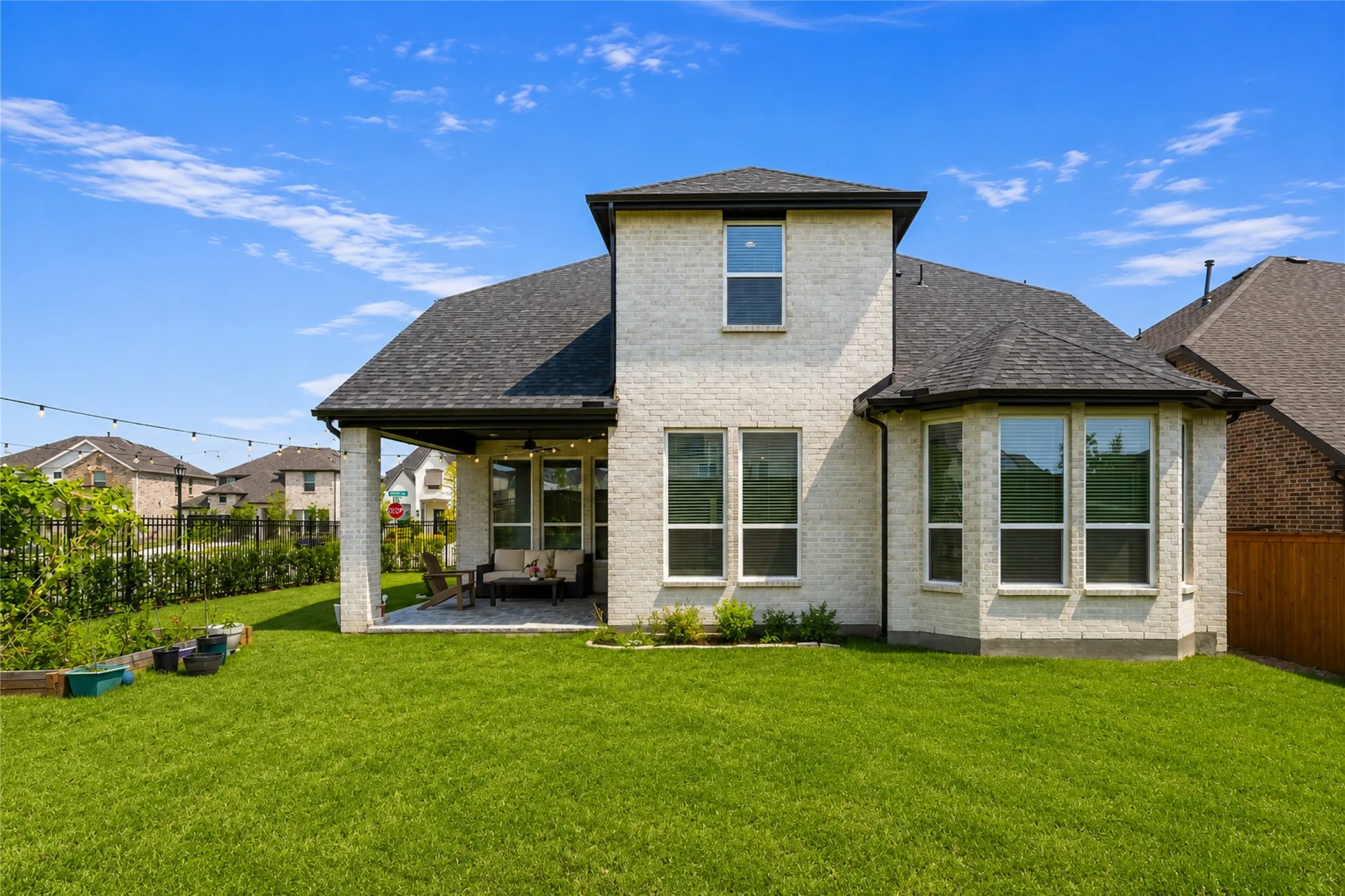 Expansive backyard featuring a manicured lawn, covered patio, and bay windows