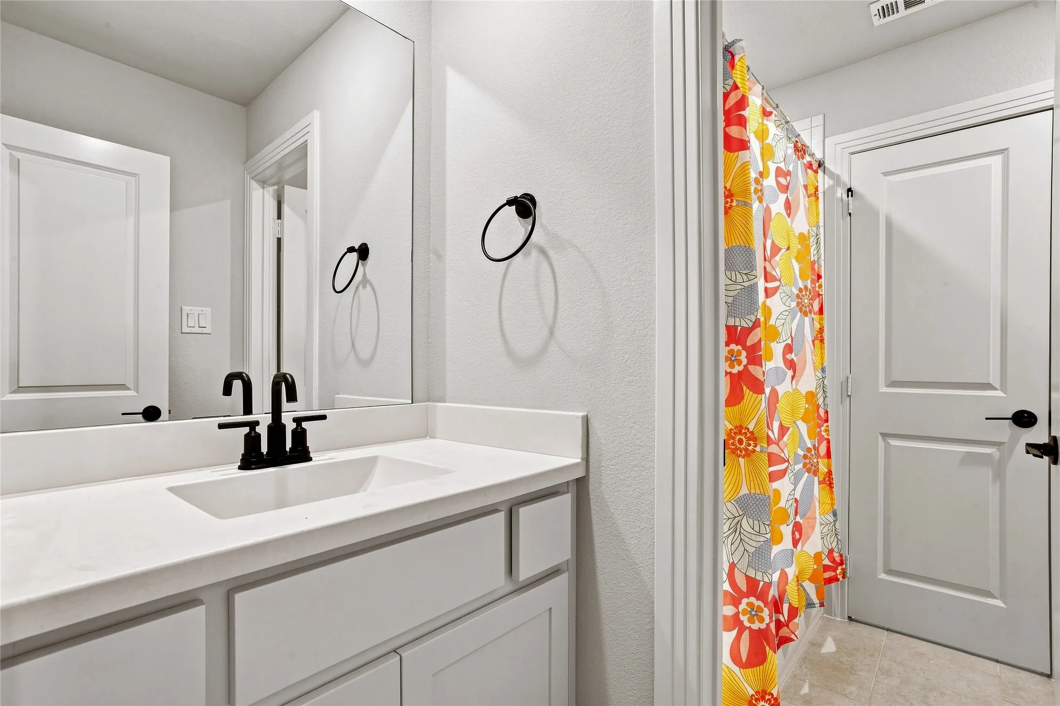 Vanity with a white countertop and integrated rectangular sink, matte black faucet, and frameless mirror