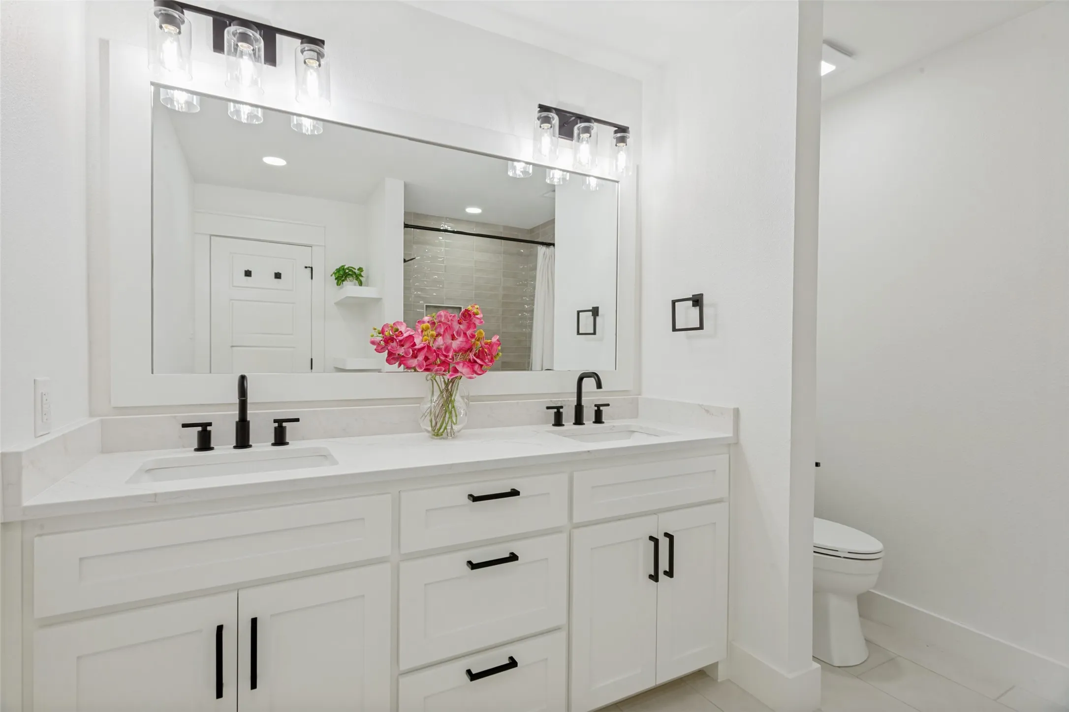 Dual vanity with stone-finish countertop, matte black fixtures, and framed mirror