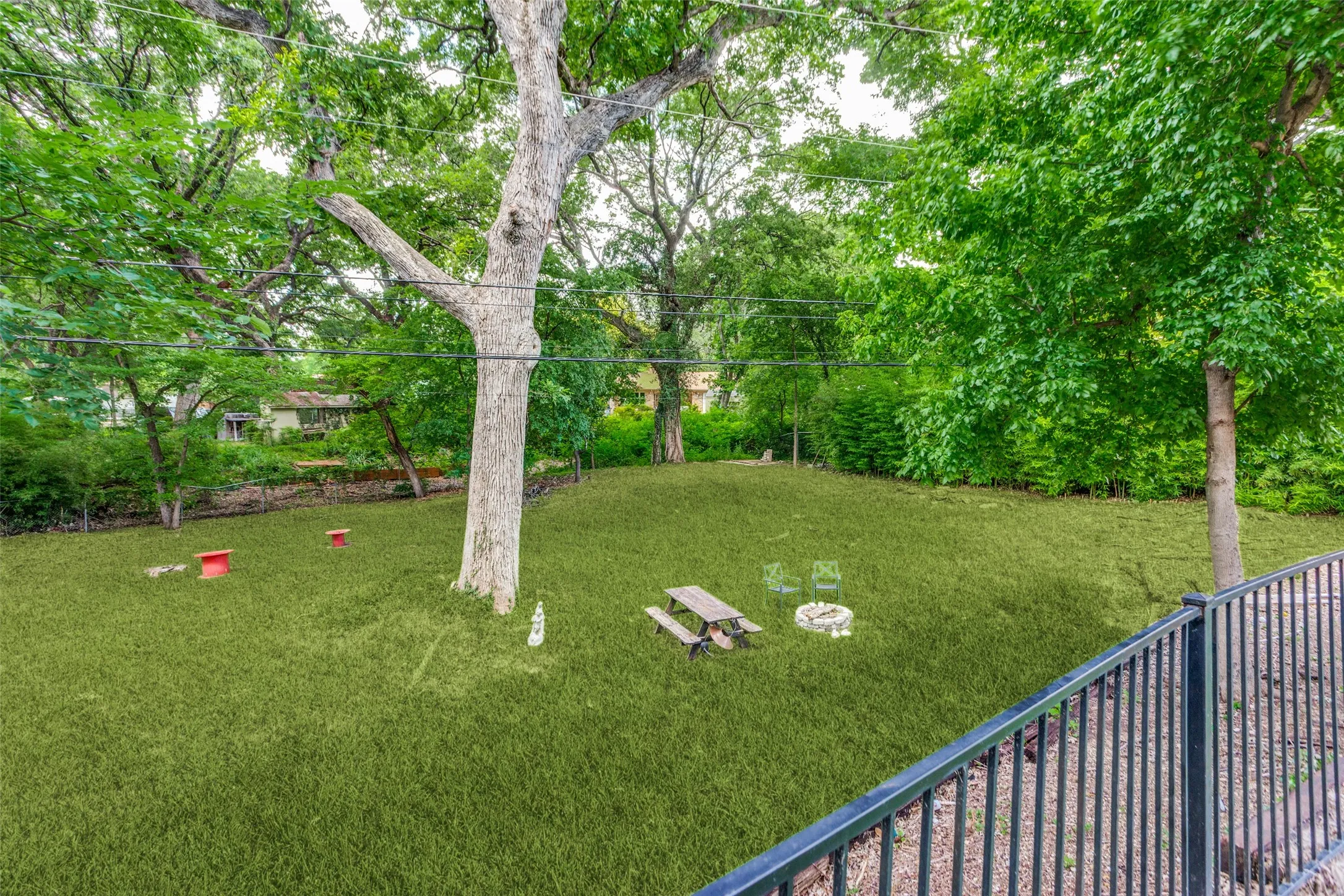 Expansive lawn area with mature trees and a black metal railing
