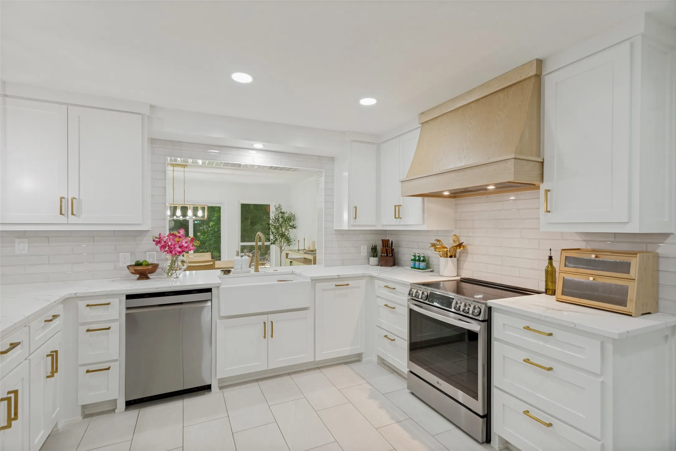 White shaker cabinetry with gold-tone hardware, stainless steel appliances, a farmhouse-style sink, white subway tile backsplash, and recessed lighting