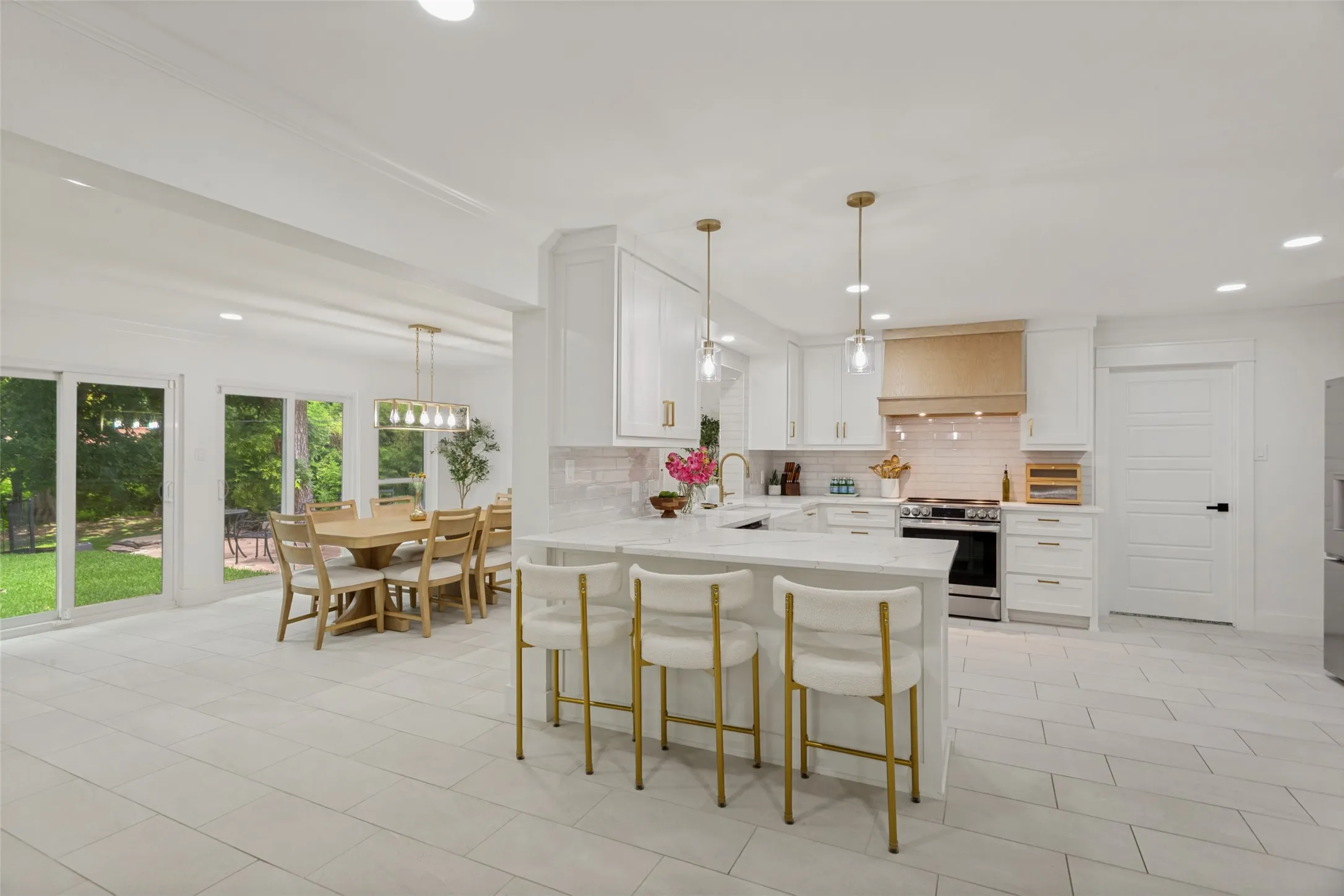 Open-concept kitchen with white cabinetry, tile backsplash, stainless steel appliances, and a central island with pendant lighting