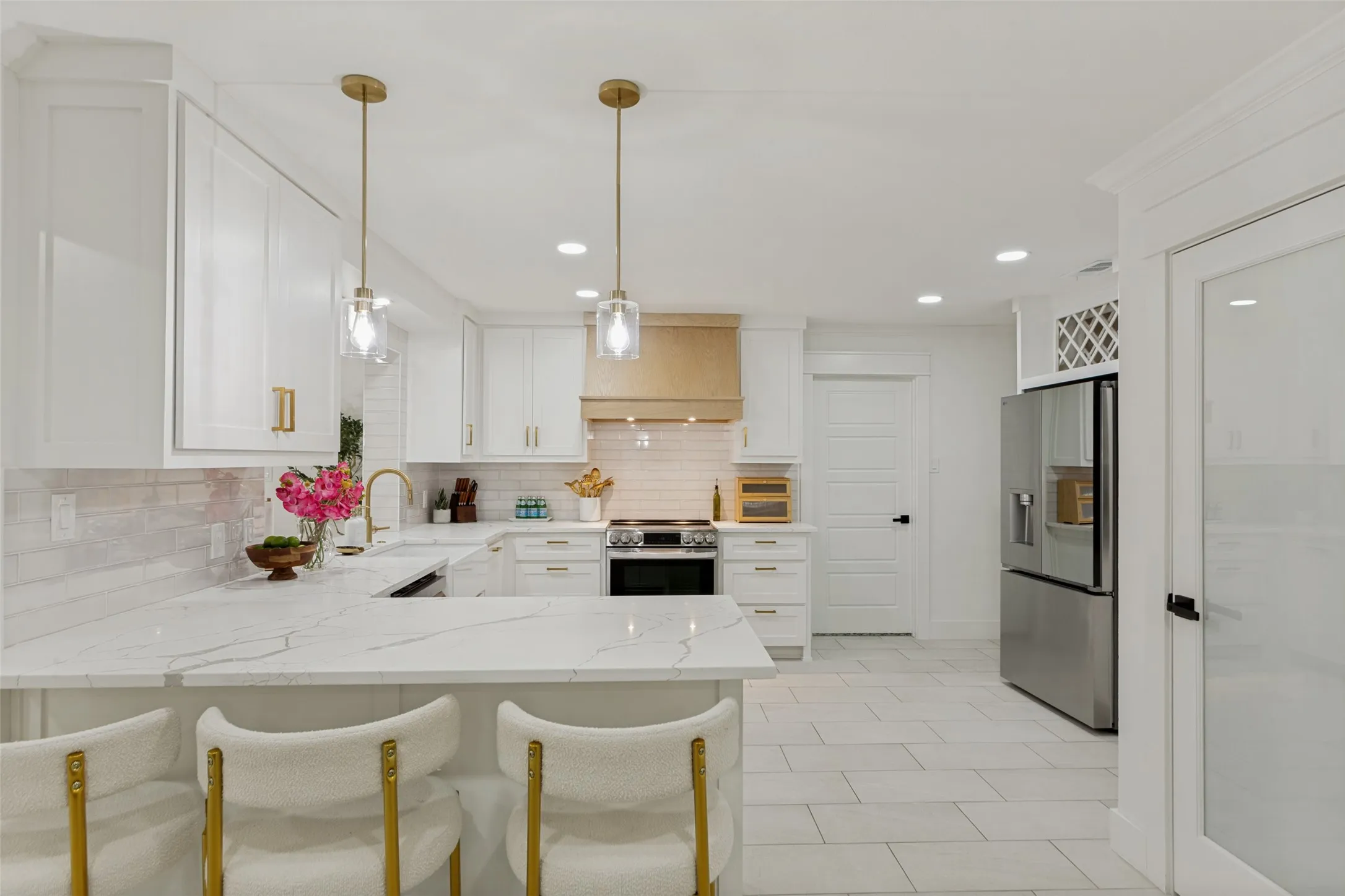 White shaker cabinetry, light-toned tile flooring, stainless steel appliances, marble-look countertops, and recessed lighting