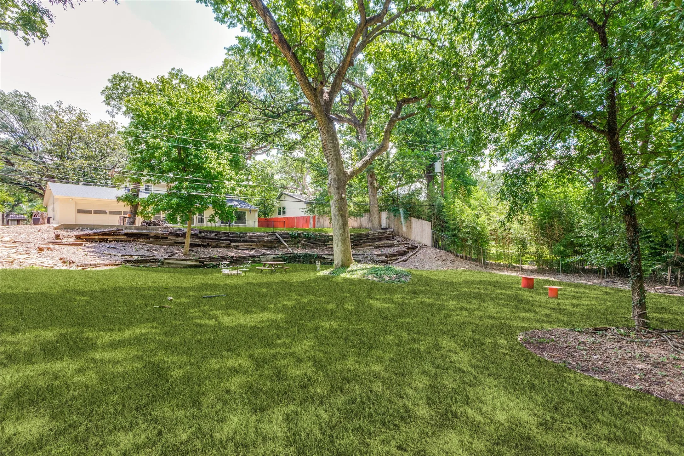 Expansive backyard featuring a manicured lawn, mature trees, and a terraced hillside