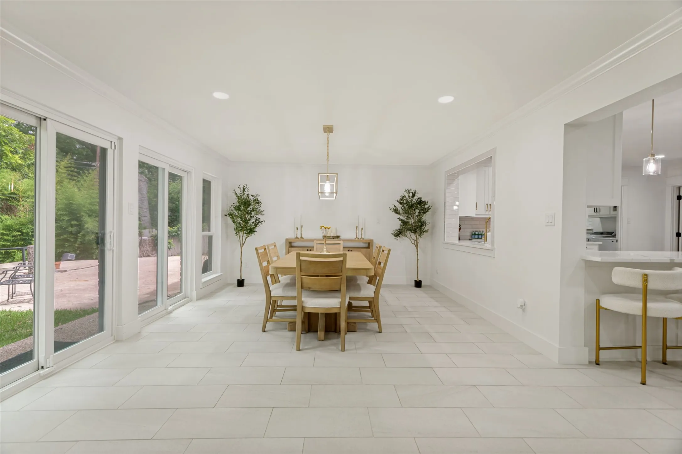 Recessed lighting, crown molding, white tile flooring, sliding glass doors, and a decorative pendant light