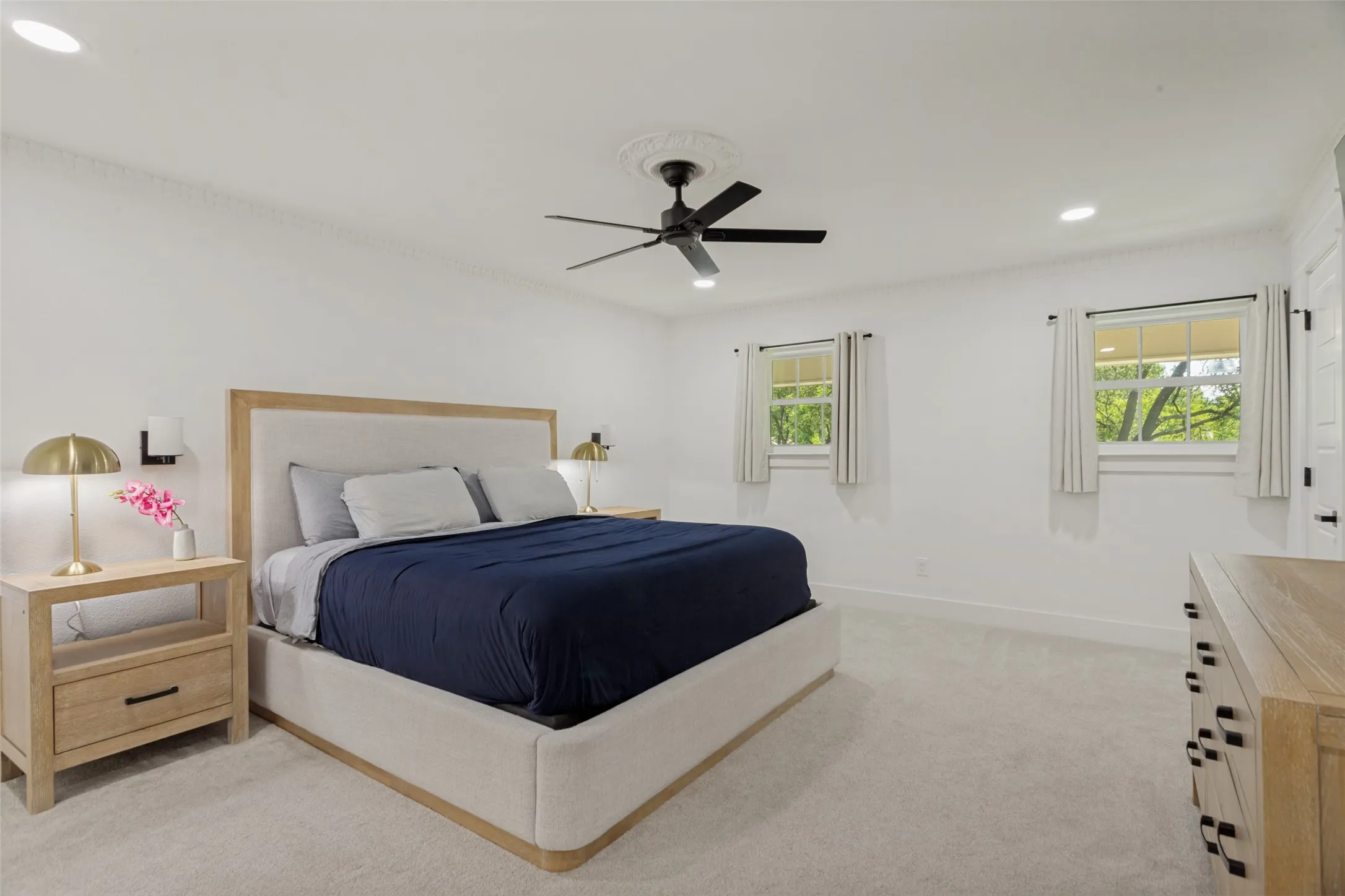 Recessed lighting and a black ceiling fan with ornate medallion