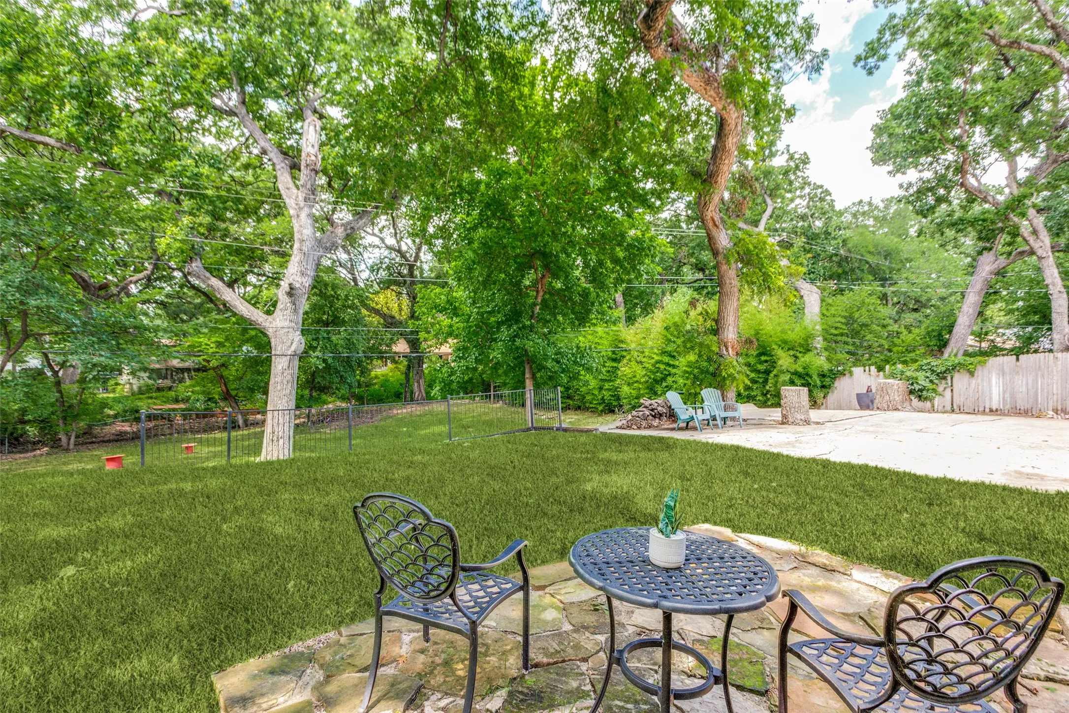 Stone patio with a manicured lawn, established trees, and a gravel area