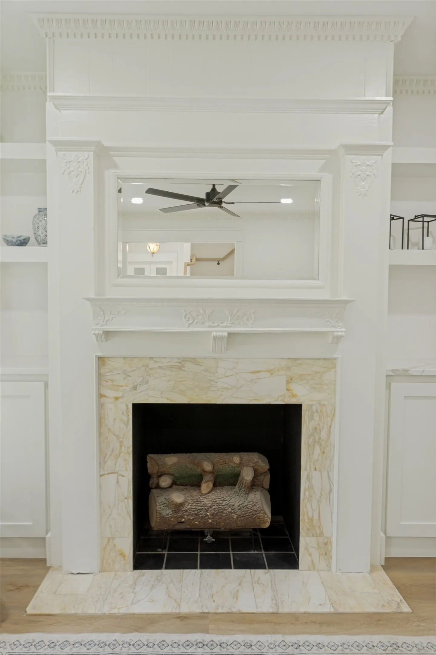 Fireplace with a stone surround, stone hearth, and a mantel, flanked by built-in shelving and cabinetry