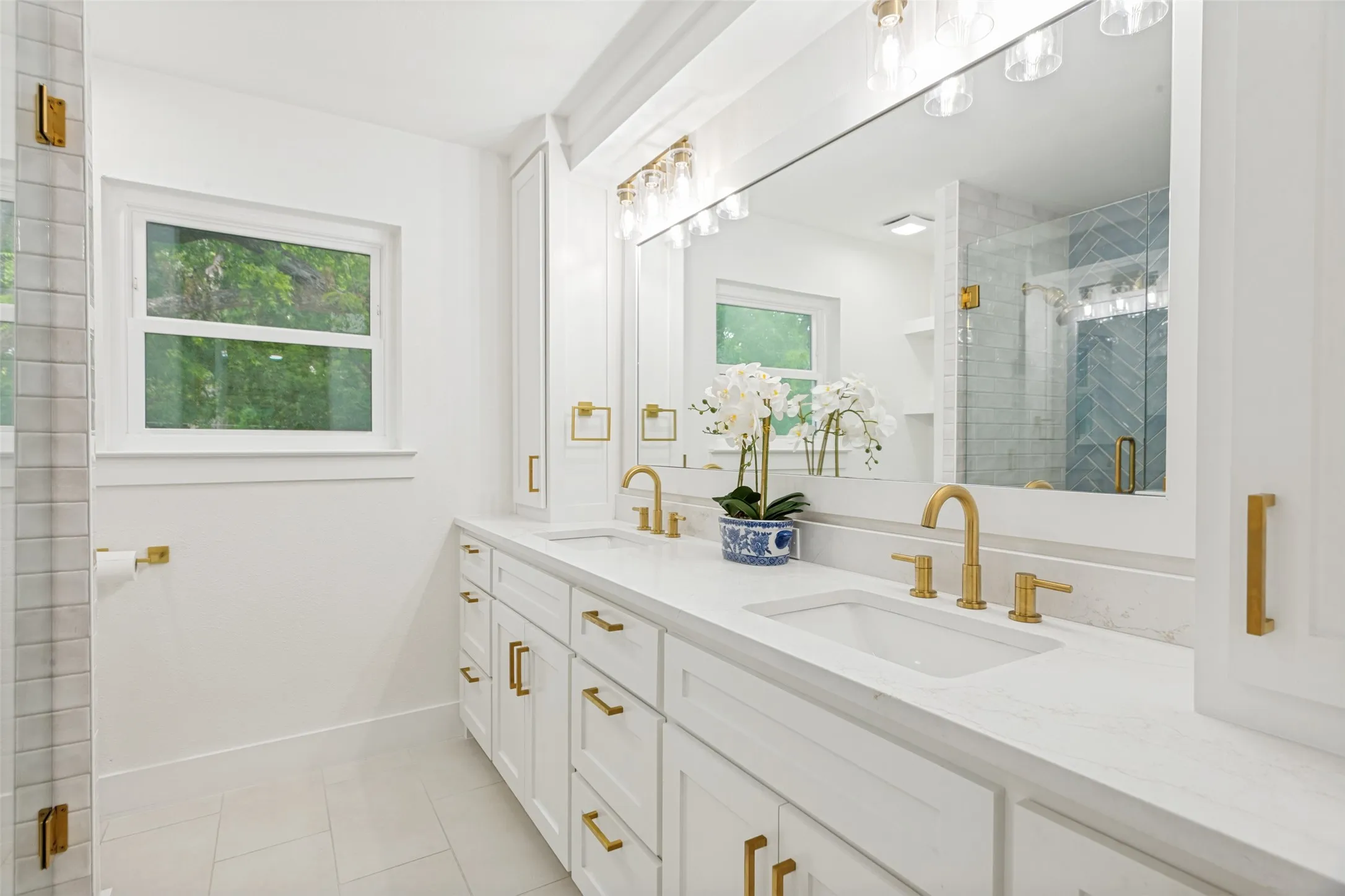 Dual vanity with white cabinetry and integrated sinks, complemented by gold-finish fixtures and hardware