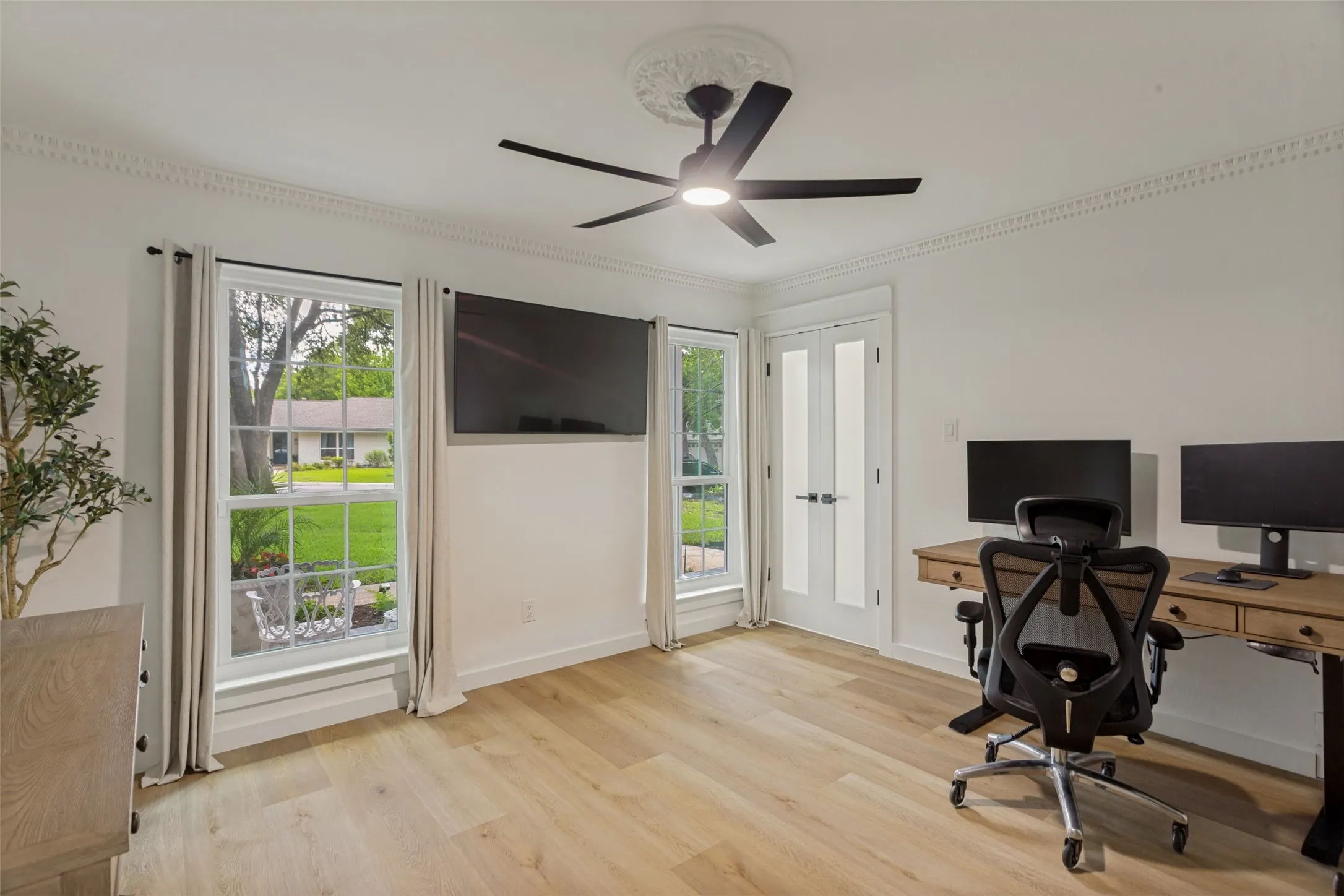 Light wood-finish flooring, white walls, and decorative crown molding