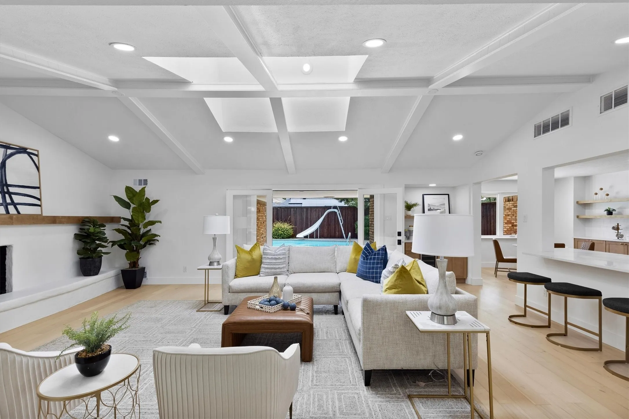 Vaulted ceiling with skylights, recessed lighting, wood-finish flooring, fireplace with a wood mantle, and sliding glass doors to outdoor area