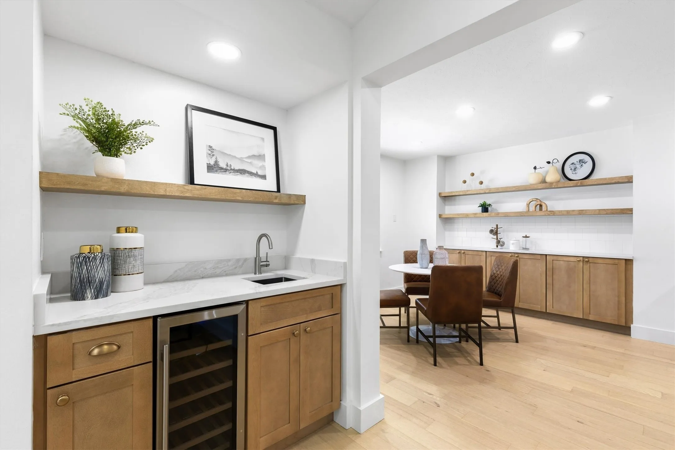 Wet bar with a stainless steel beverage refrigerator, light wood-finish cabinetry, and a stone countertop