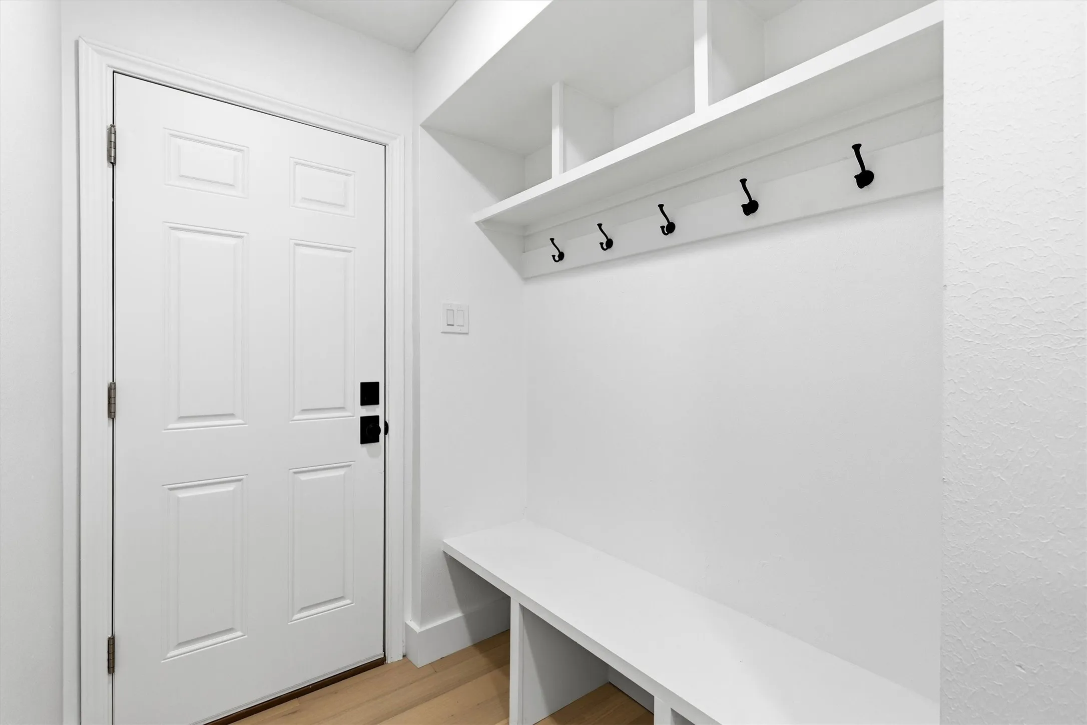 Built-in mudroom bench with storage cubbies, integrated shelving, and wall-mounted coat hooks