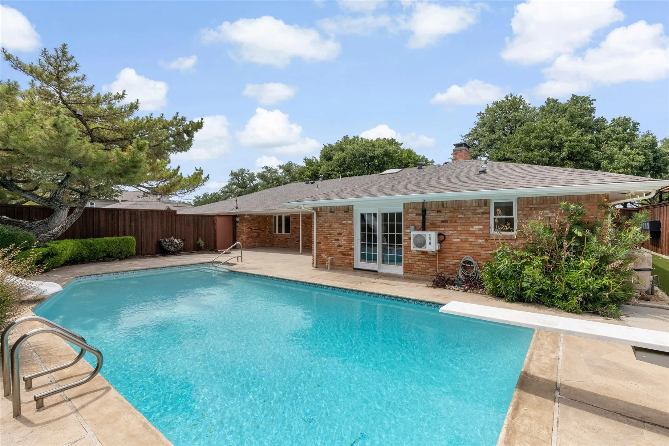 Rectangular swimming pool with a diving board, surrounded by concrete decking