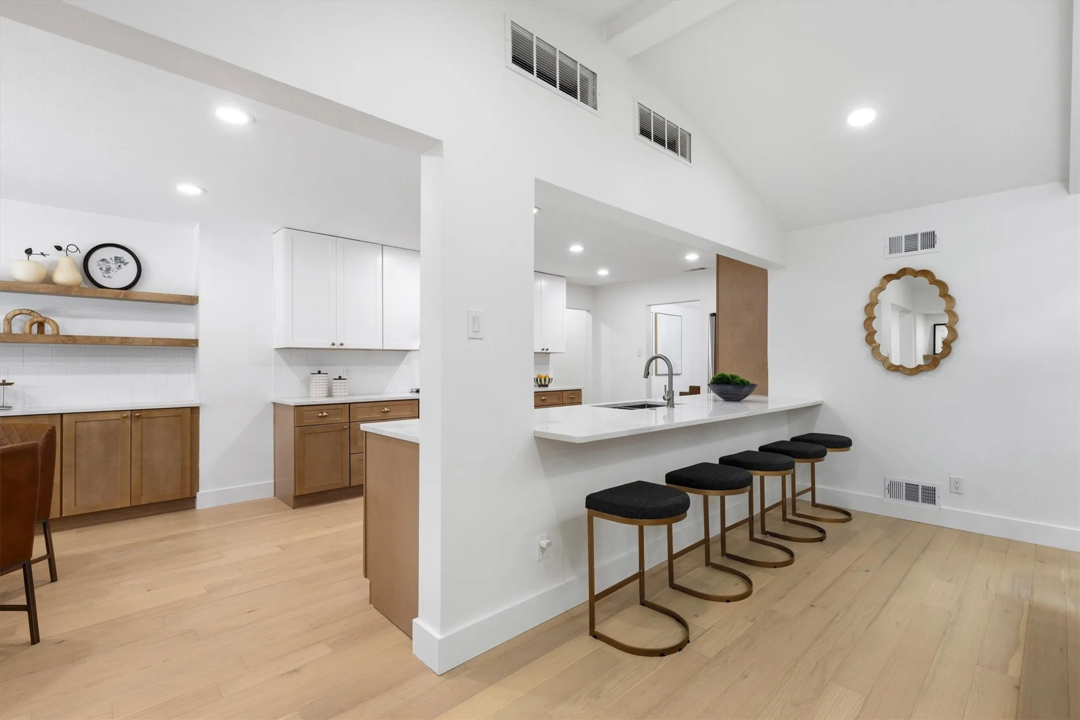 Vaulted ceiling with transom windows, recessed lighting, wood-finish flooring, built-in kitchen cabinetry, and a kitchen island with seating