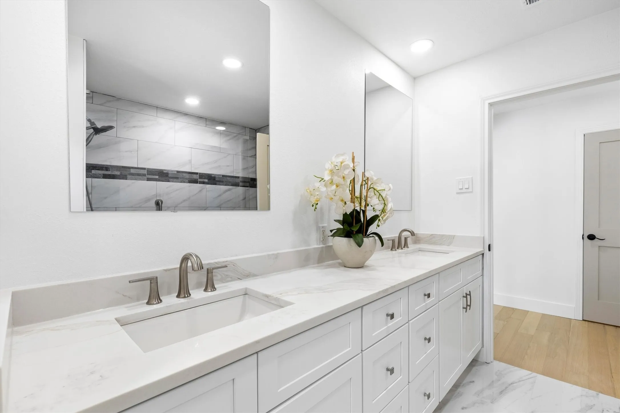 Dual vanity with white shaker-style cabinetry, undermount sinks, and brushed nickel hardware