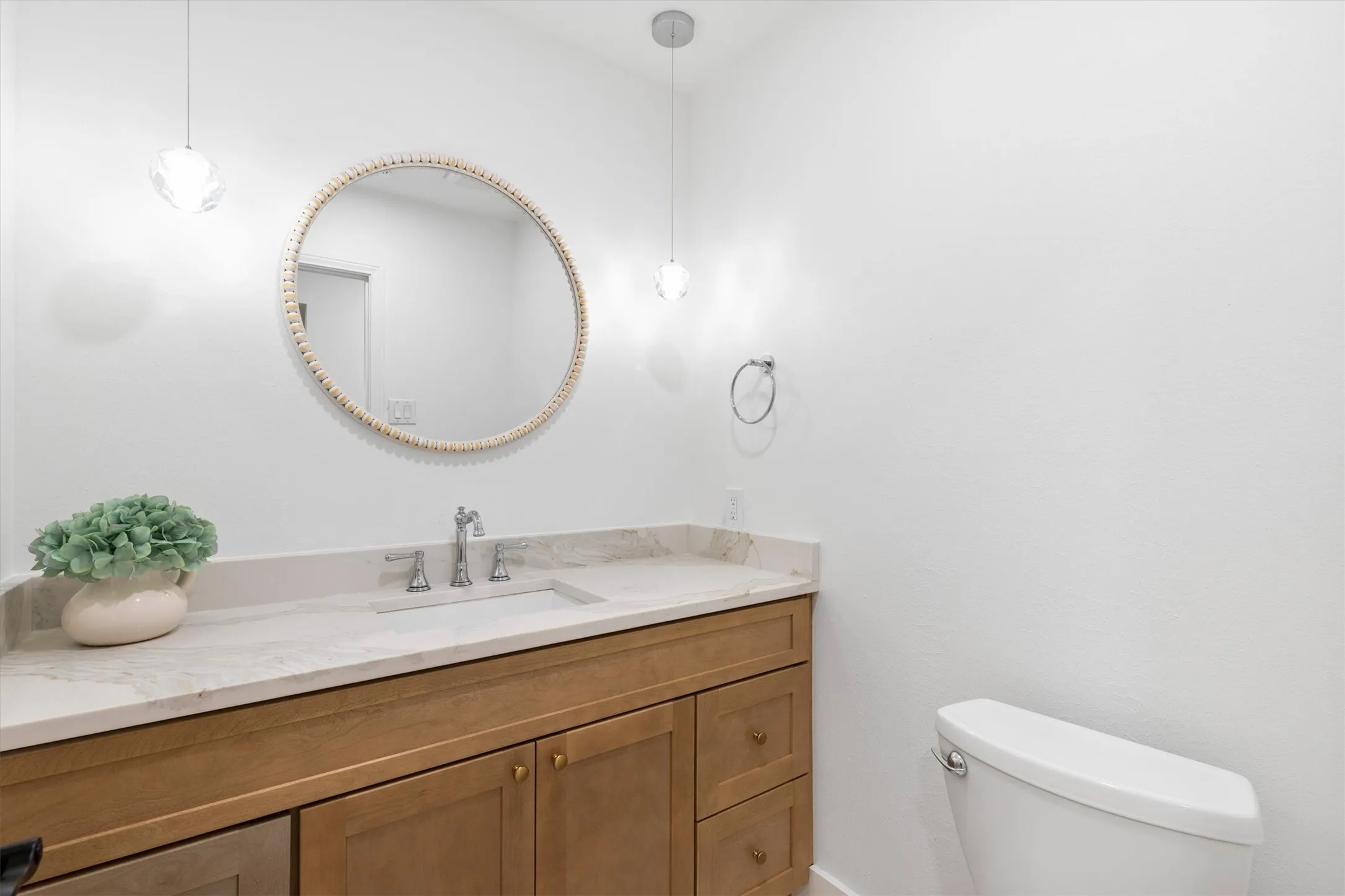 Wood-finish vanity with an integrated sink, polished chrome faucet, and stone countertop