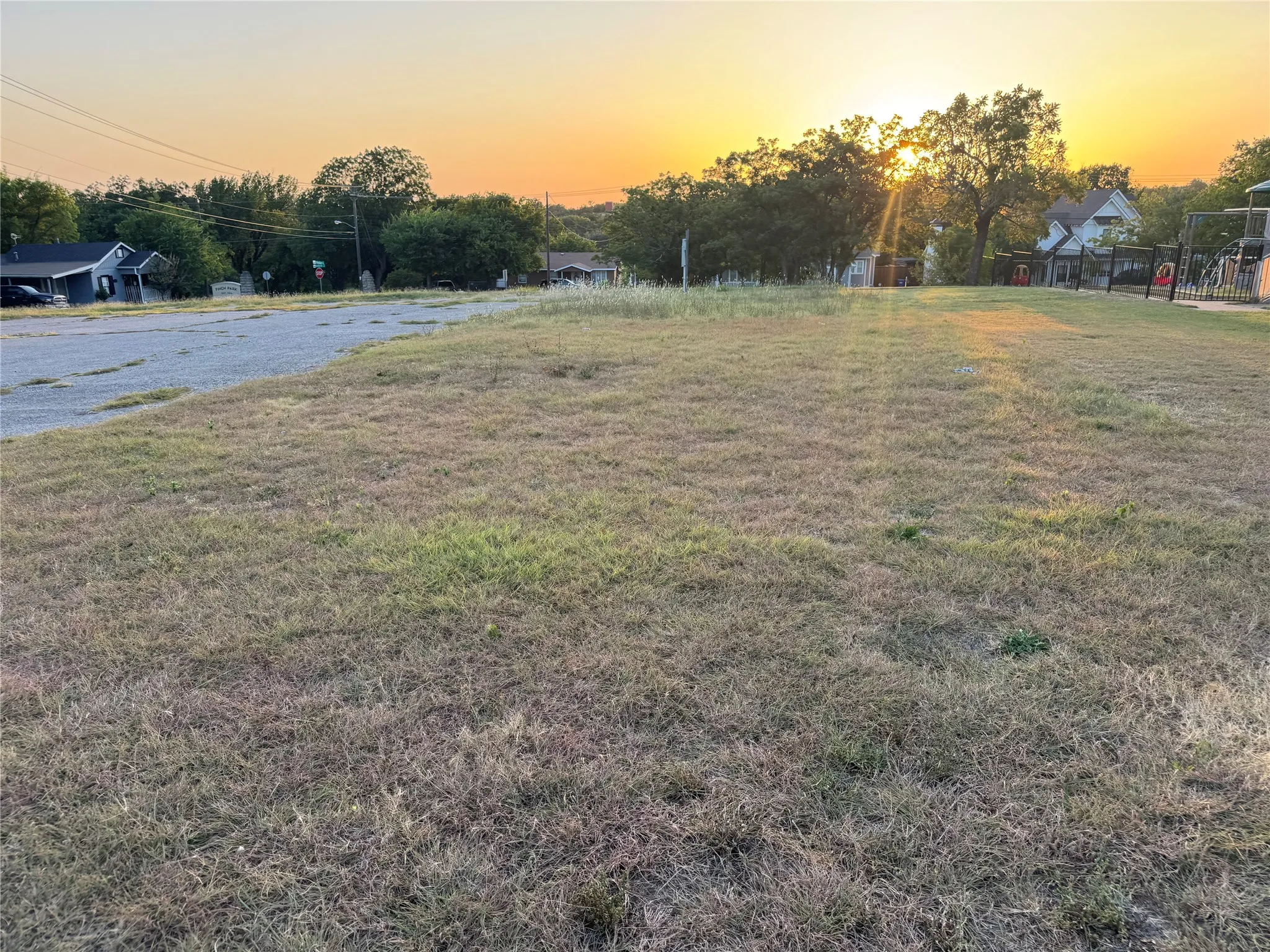 Expansive grassy lot with a partially paved area