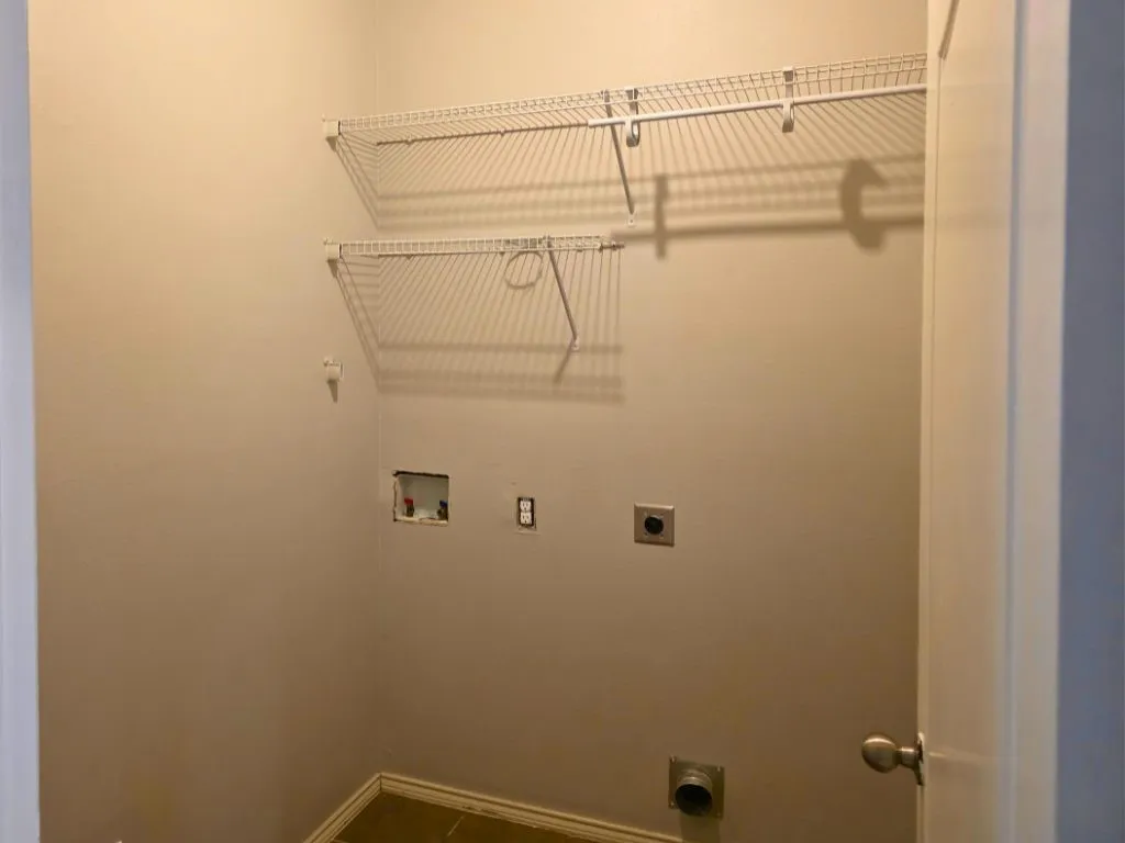 Utility room with two levels of wire shelving, a dryer vent hookup, and a washer hookup