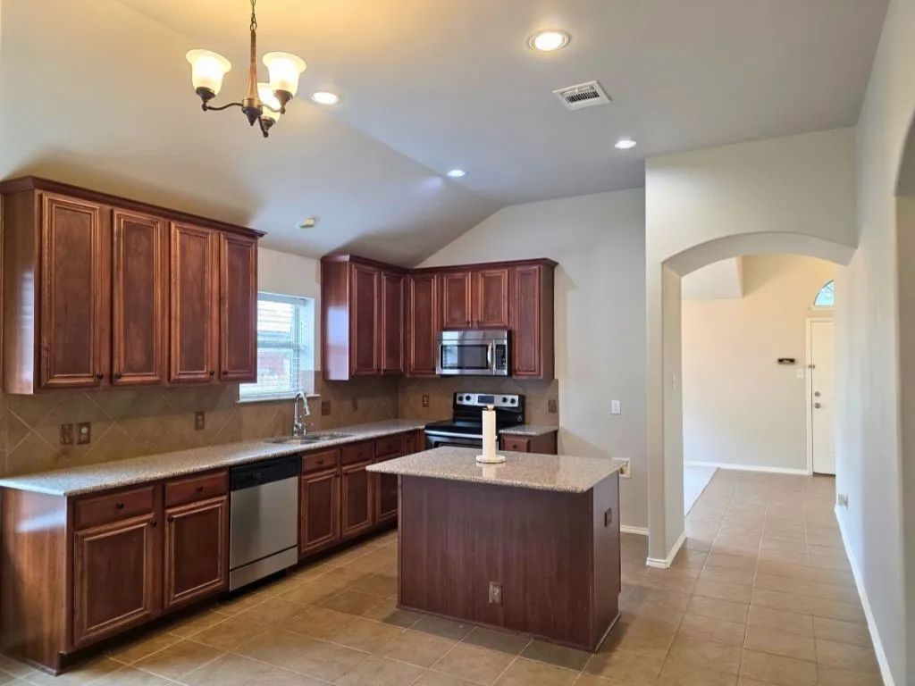 Kitchen featuring wood cabinetry, light-toned countertops, a tile backsplash, and stainless steel appliances