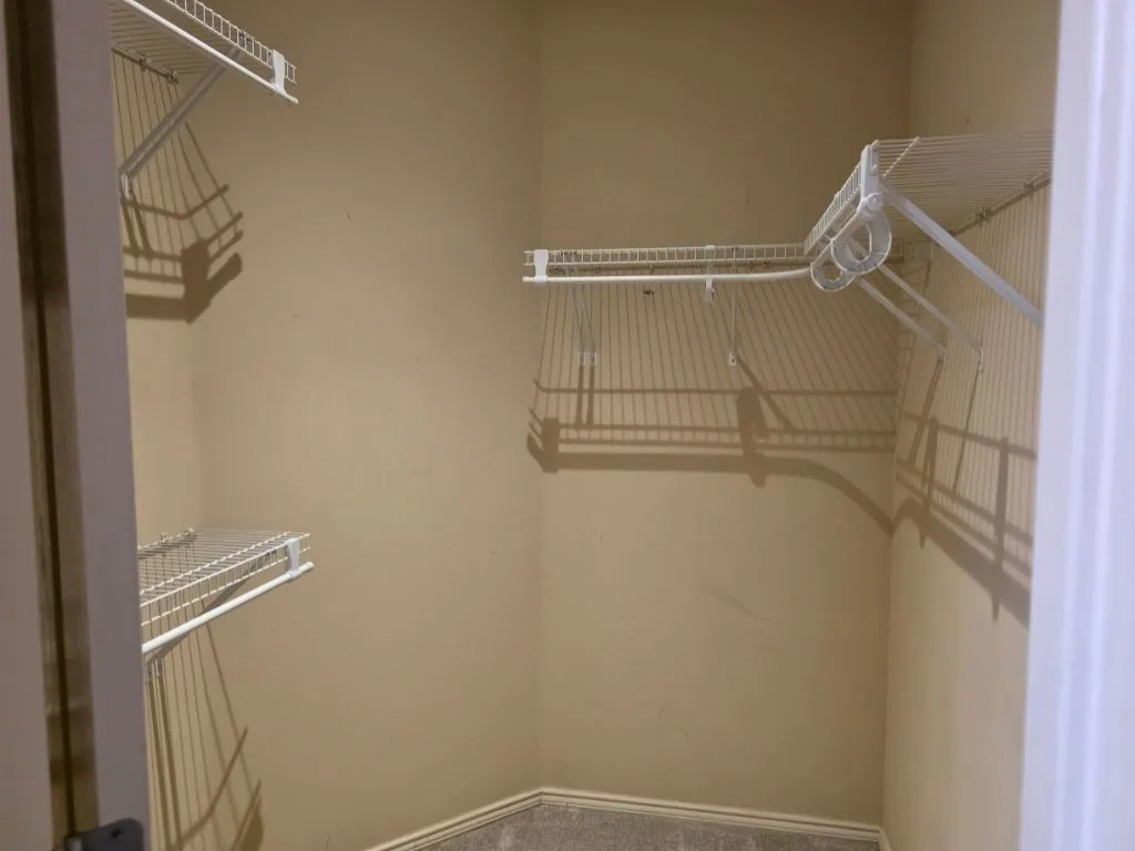 Walk-in closet featuring wire shelving and hanging rods, neutral wall paint, and gray carpet flooring
