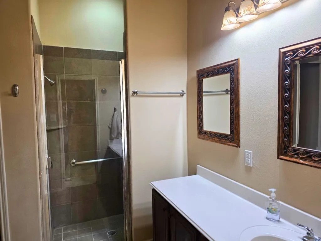 Bathroom featuring a glass-enclosed shower with tile surround, a built-in shower bench, and a grab bar