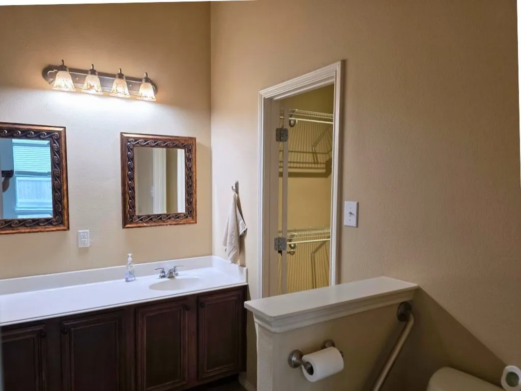 Double vanity with dark wood-finish cabinetry, white countertop, and two framed mirrors