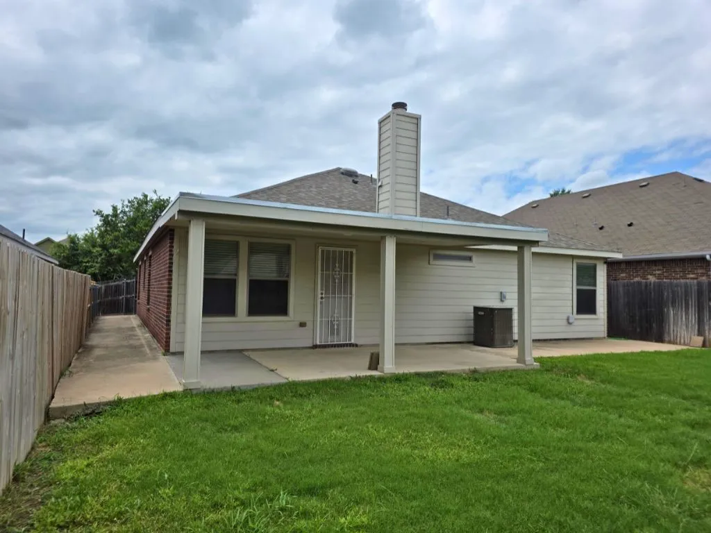 Expansive backyard featuring a covered patio, manicured lawn, and privacy fencing