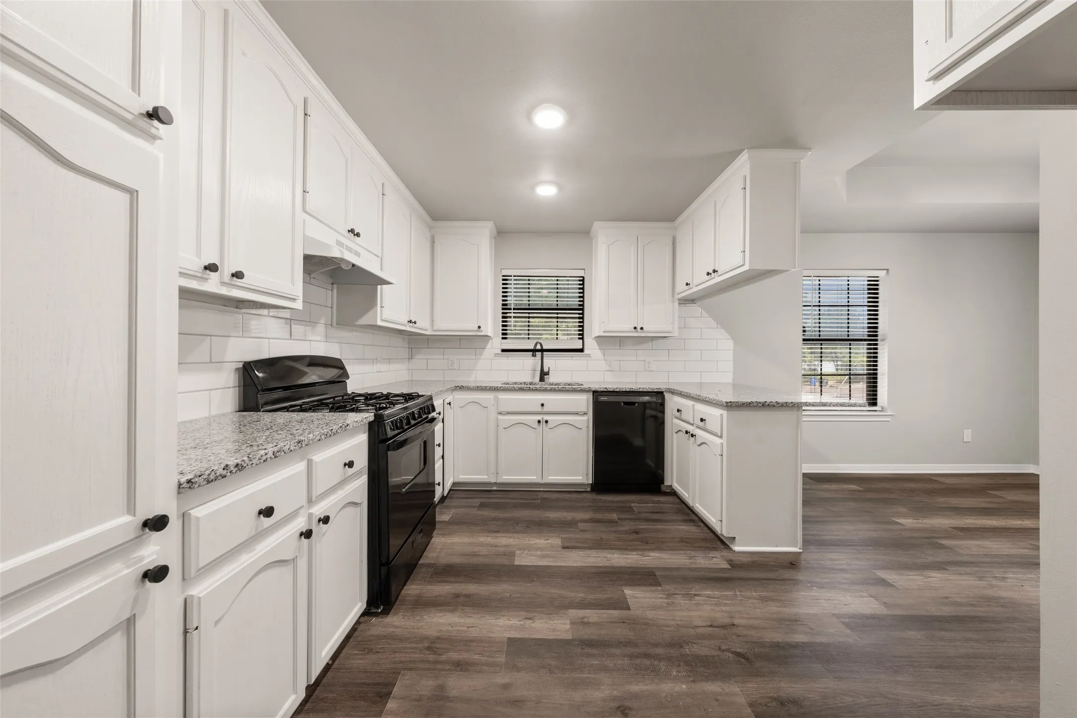 Kitchen featuring white cabinetry, granite countertops, subway tile backsplash, and wood-finish flooring