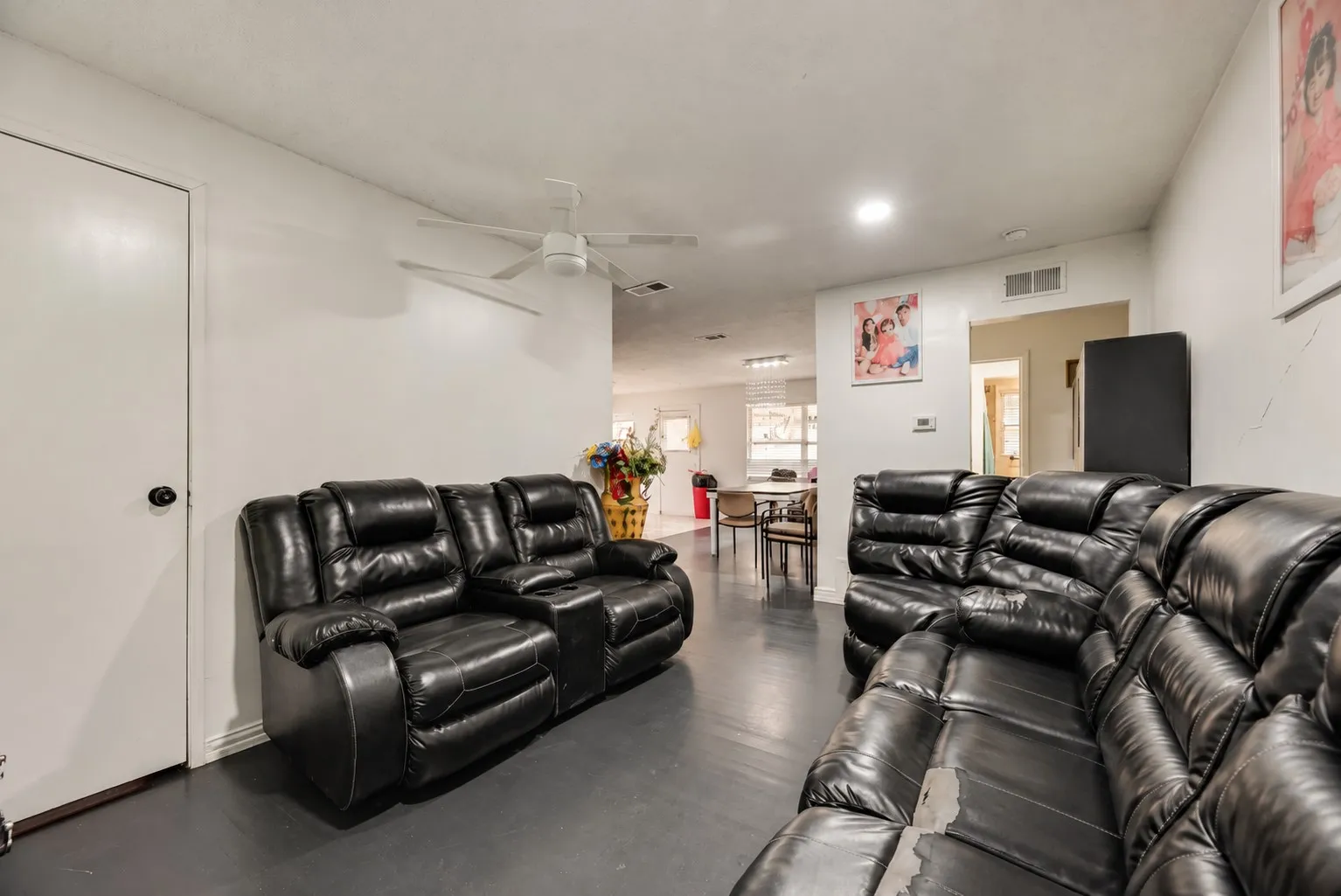 White walls, dark wood-finish flooring, and a ceiling fan with integrated lighting