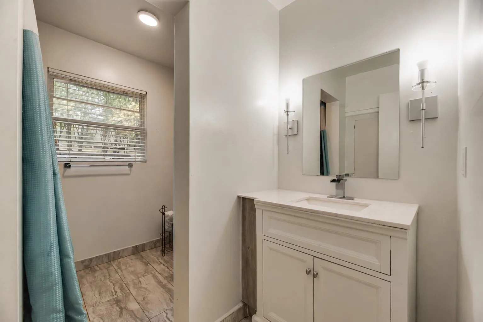 White vanity with a rectangular undermount sink and chrome faucet