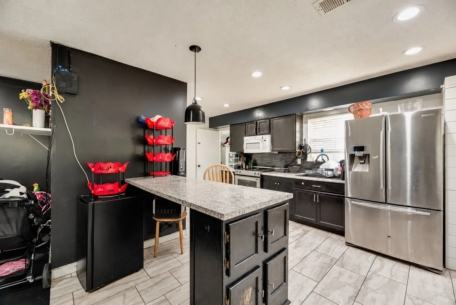 Kitchen with wood-finish flooring, dark cabinetry, and light-toned countertops