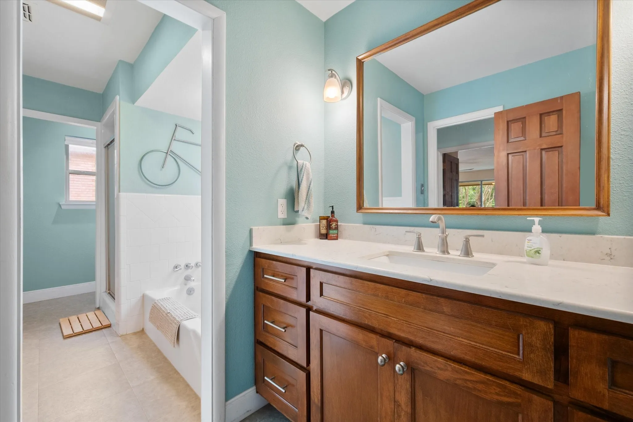 Updated cabinetry in the primary bath with quartz vanity with an integrated sink and brushed nickel hardware.