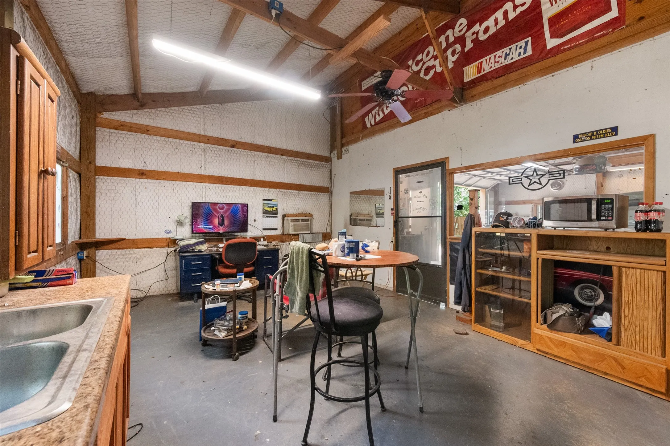 Inside the Shop is a separate office area with a window unit plus a sink, cabinetry & counterspace, refrigerator and window looking out to the shop.