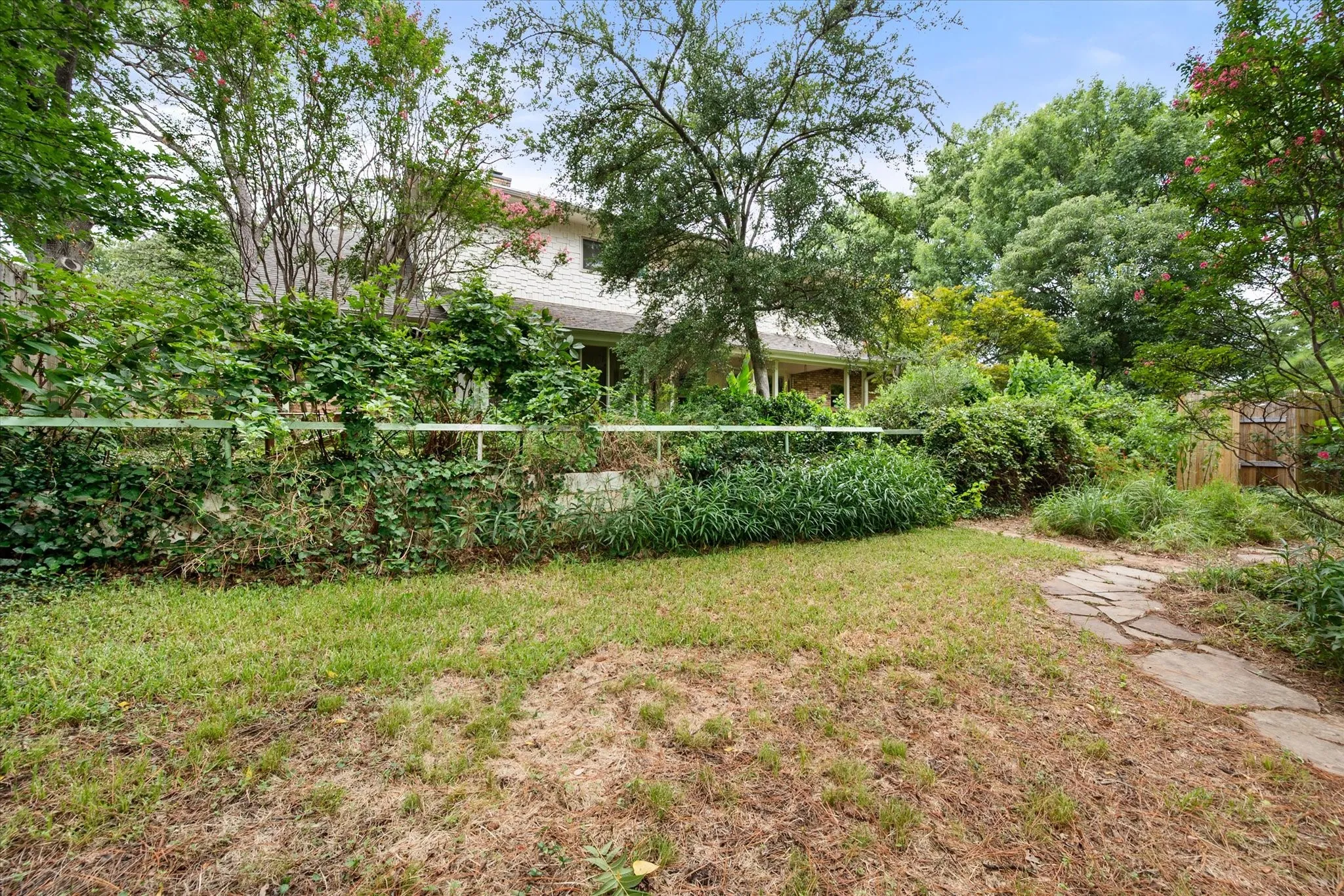 Backyard with flagstone pathway, mature trees, and established plantings....there is an outdoor shower area too!